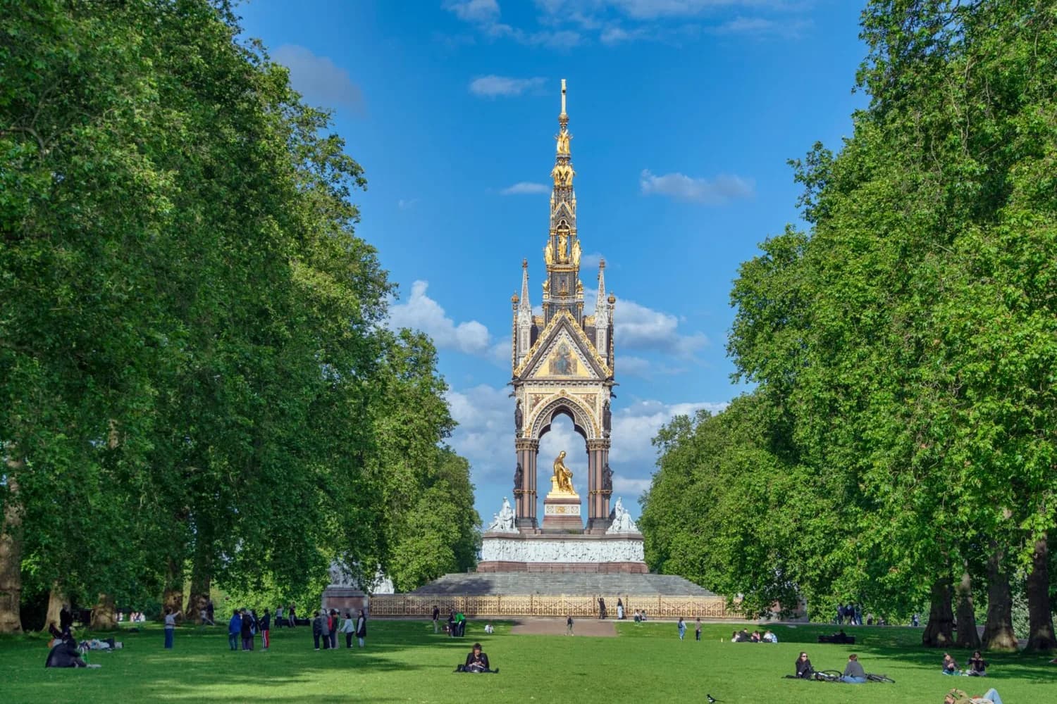 Kaiser-Albert-Denkmal im Hyde Park London, goldene Statue unter gotischem Marmorbogen, umliegende Parkrasen und Bäume mit entspannenden Besuchern