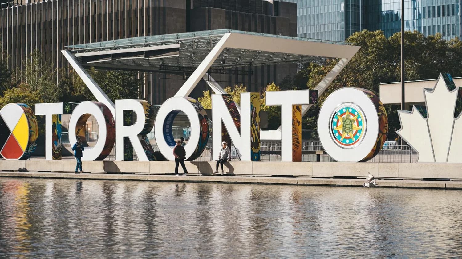 Toronto Schriftzug am Nathan Phillips Square in Kanada mit Menschen am Wasser und moderner Stadtkulisse