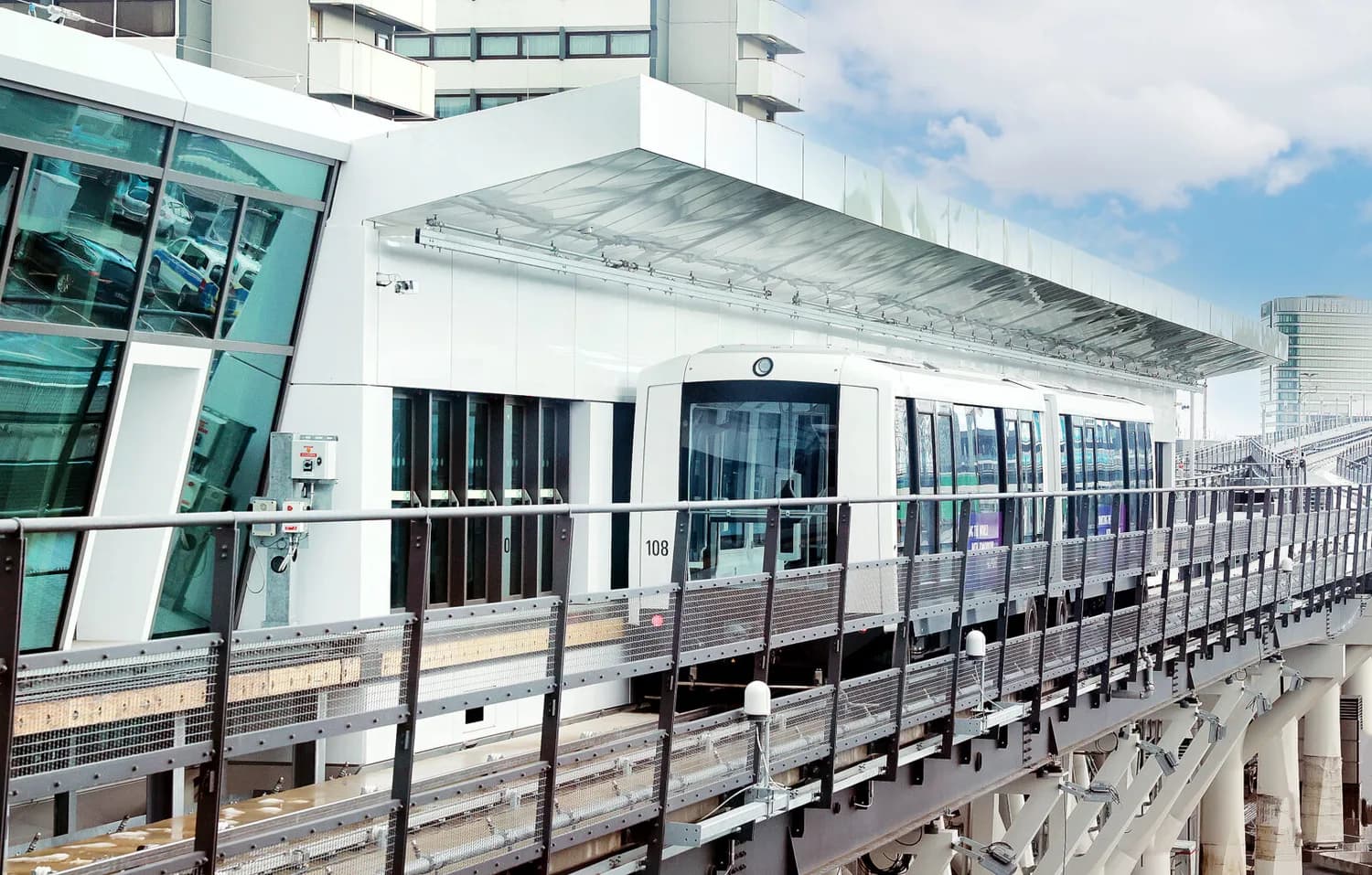 SkyLine automatische Flughafenbahn in Frankfurt am Main an erhöhtem Bahnhofssteg, moderner weißer Zug am Bahnsteig vor Glasfassade
