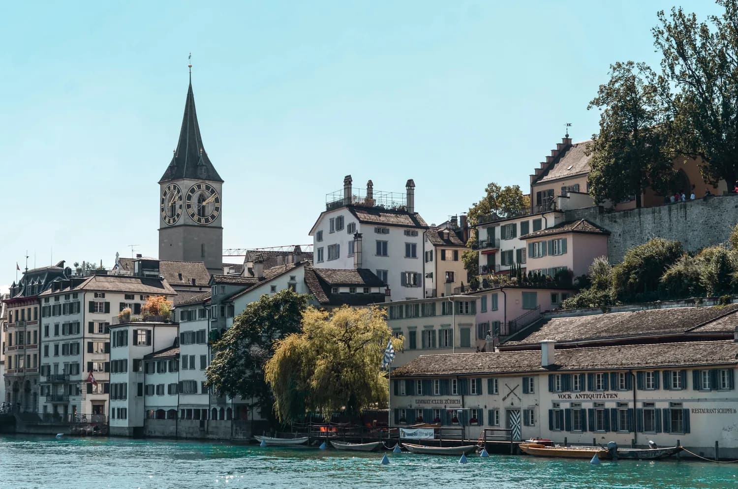 Altstadt von Zürich mit Uferhäusern, Stadtkirche St. Peter mit großem Zifferblatt und Booten auf der Limmat