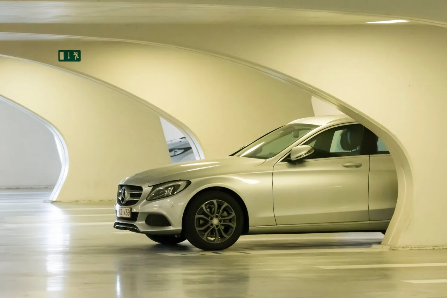 Silberner Mercedes geparkt in modernem mehrstöckigen Parkhaus mit geschwungenen Betonöffnungen, Flughafen München Parken Guide Szene