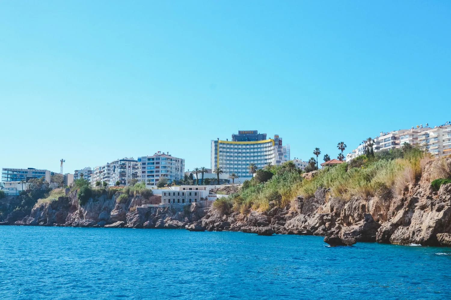 Panorama der türkischen Riviera bei Antalya mit Felsküste, blauem Meer, Palmen und Hotel- und Wohngebäuden am Ufer