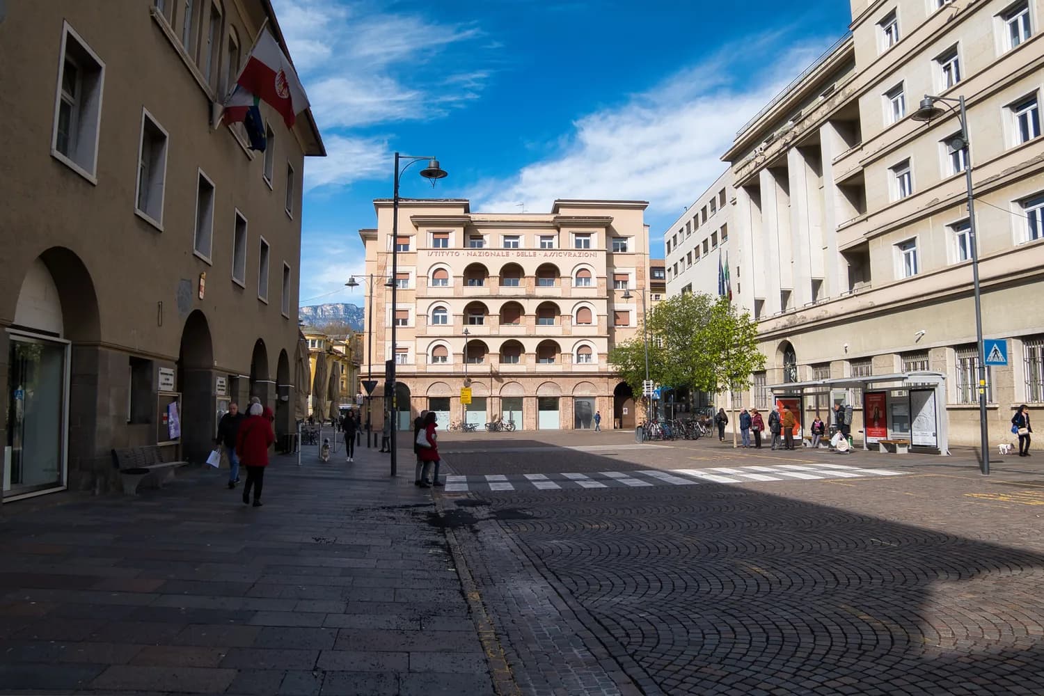 Bozen Altstadt Fußgängerzone mit historischem Arkadenhaus, Passanten, Buswartehalle und Blick auf Alpenkulisse