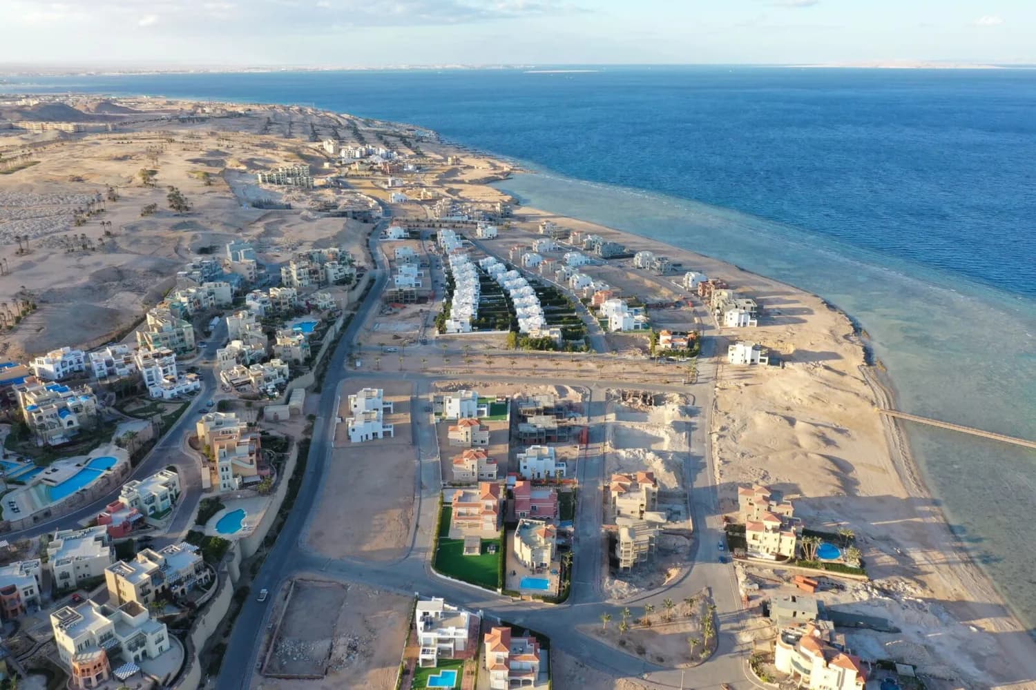 Luftaufnahme von Küstenresorts und Villen mit Pool entlang des Roten Meeres in Hurghada, Strand, Reihenhäuser und unbebaute Wüstenflächen am Ufer