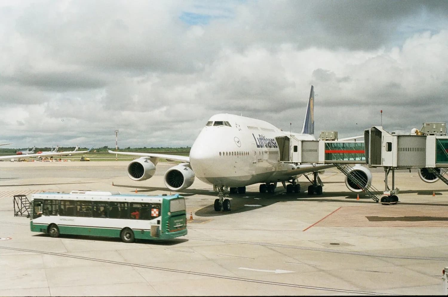 Lufthansa Großraumflugzeug am Gate mit Fluggastbrücke und Bus am Flughafen, wartende Triebwerke und Rollfeldscene