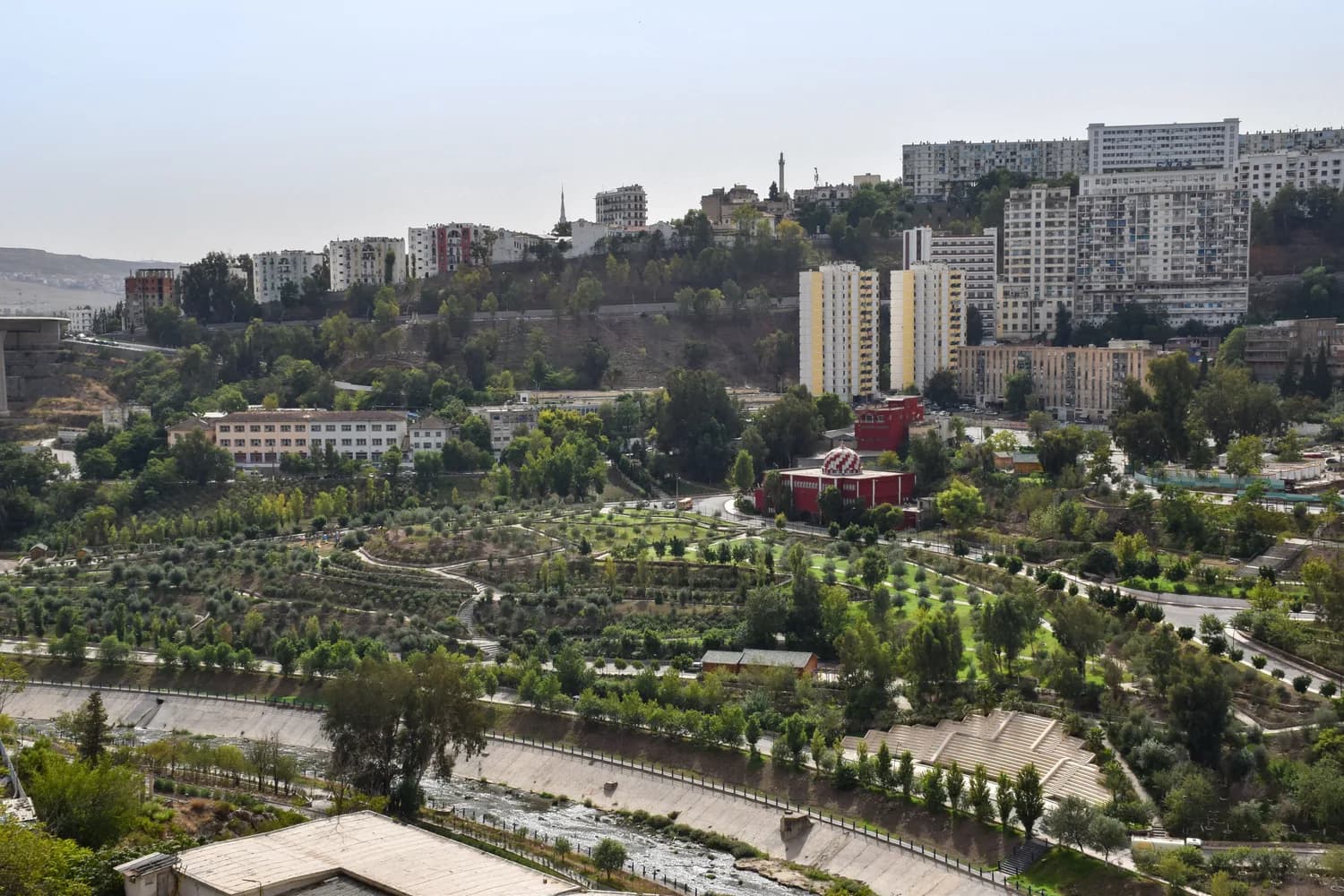 Luftaufnahme von Algiers mit Uferpark, grünen Terrassen, Flusslauf und Wohnhochhäusern im Hintergrund