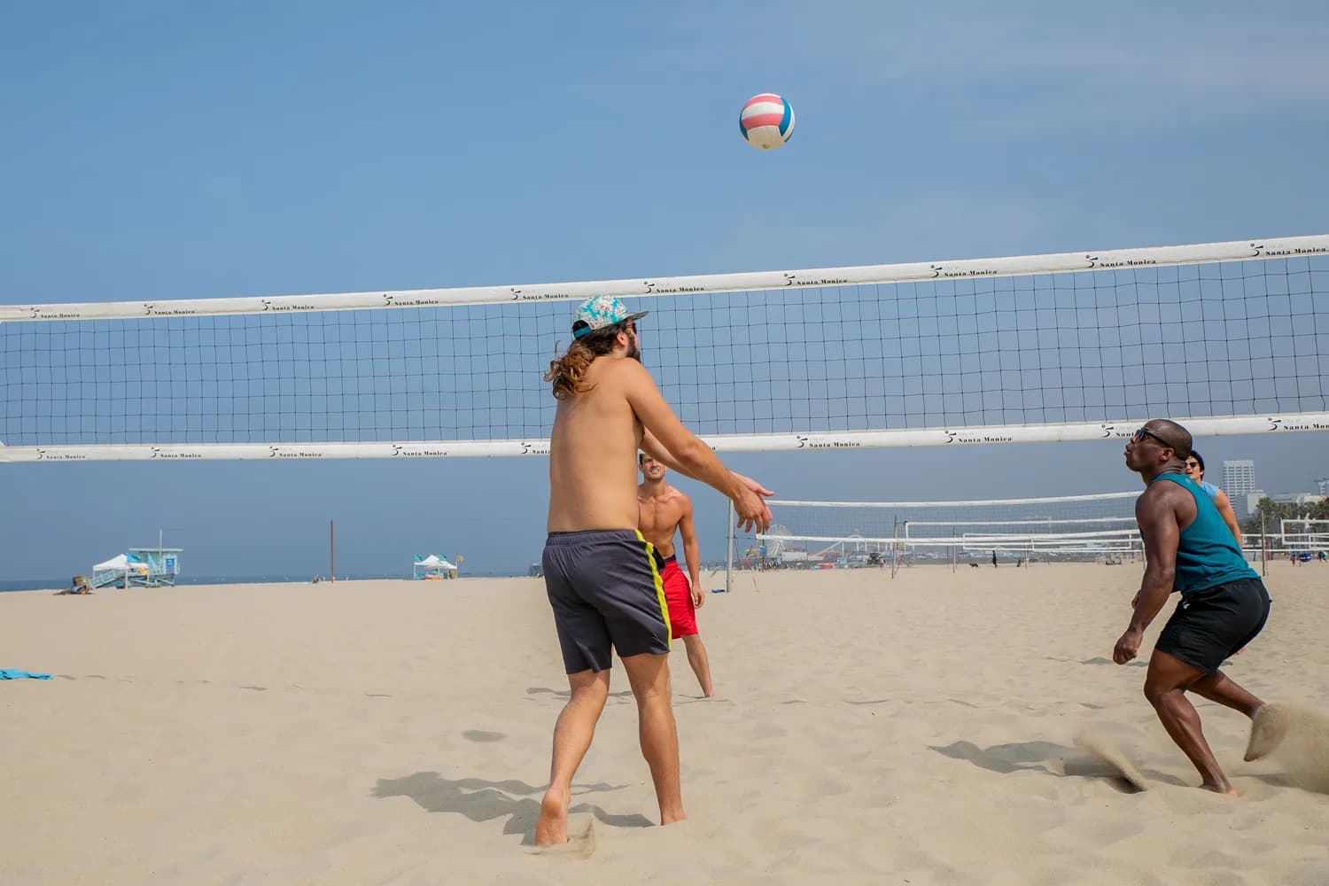 Freunde spielen Beachvolleyball am Strand auf Mallorca im Sommerurlaub