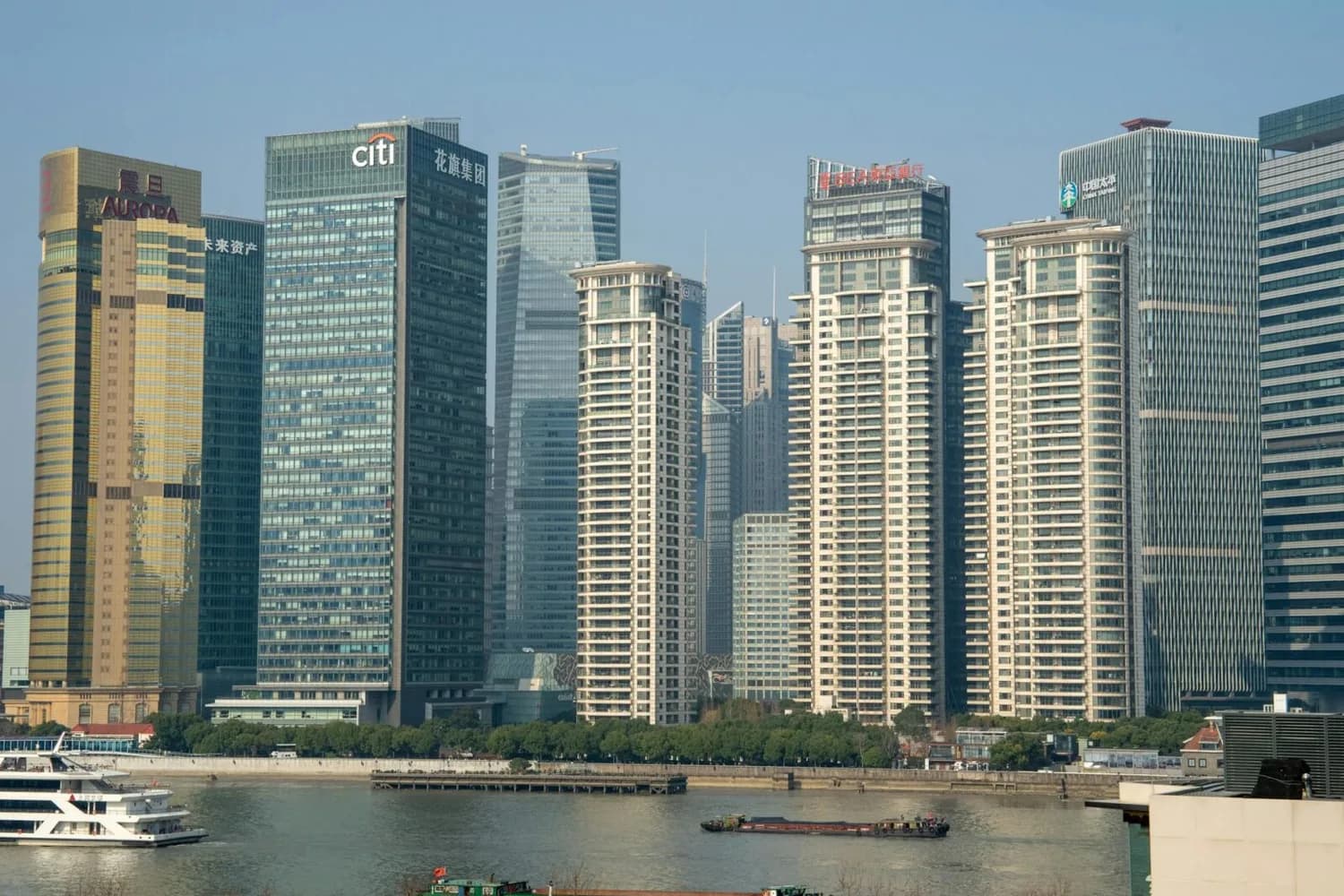 Horizont von Shanghai mit Hochhäusern und Flussfront, Wohn- und Bürogebäude sowie Ausflugsboot auf dem Huangpu-Fluss