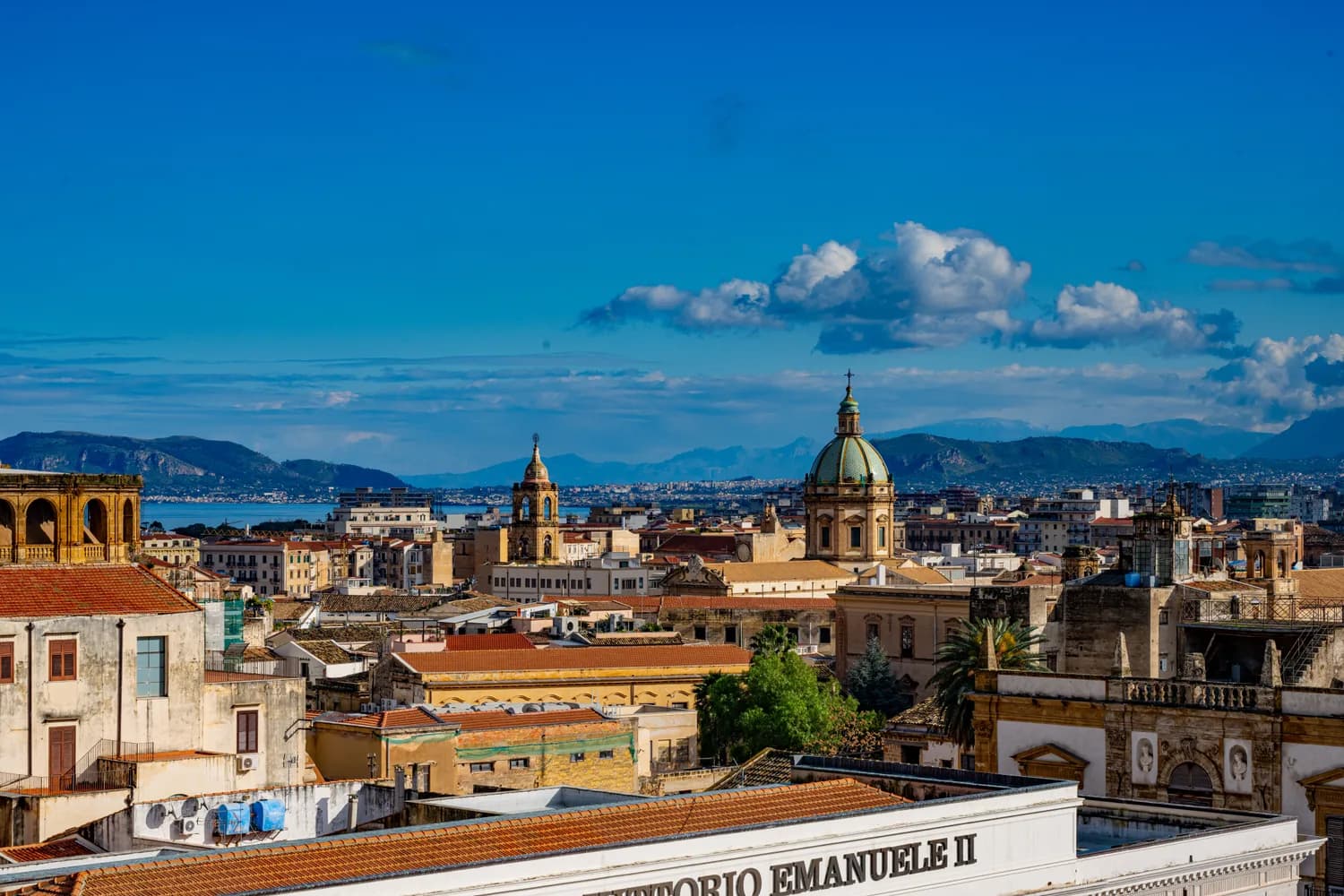 Panoramablick über die Dächer von Palermo mit barocker Kuppel, Kirchturm, mediterranen Gebäuden und Bergen am Horizont