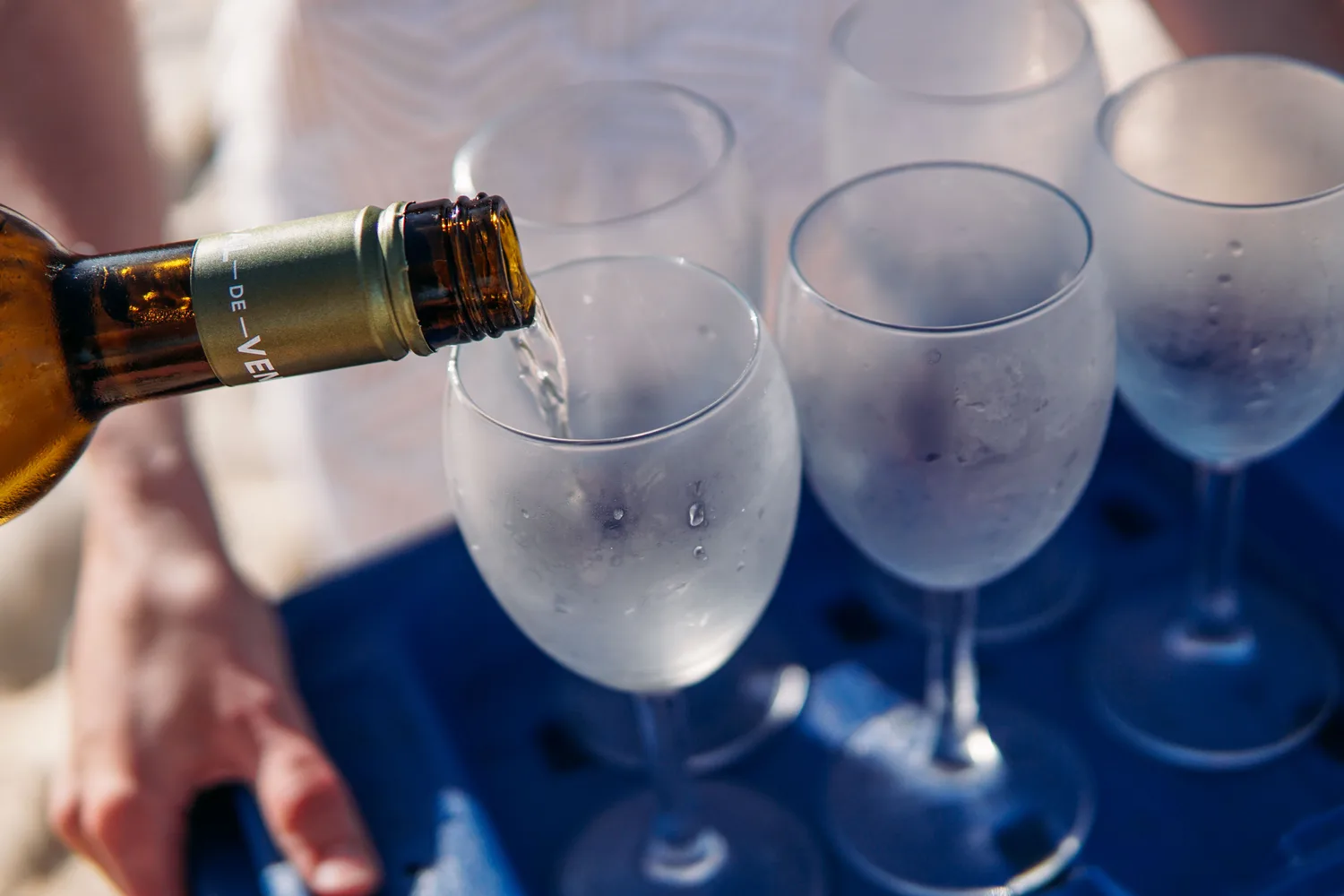 Weißwein wird an einer Strandbar in Paguera auf Mallorca eingeschenkt, im Hintergrund die Küste
