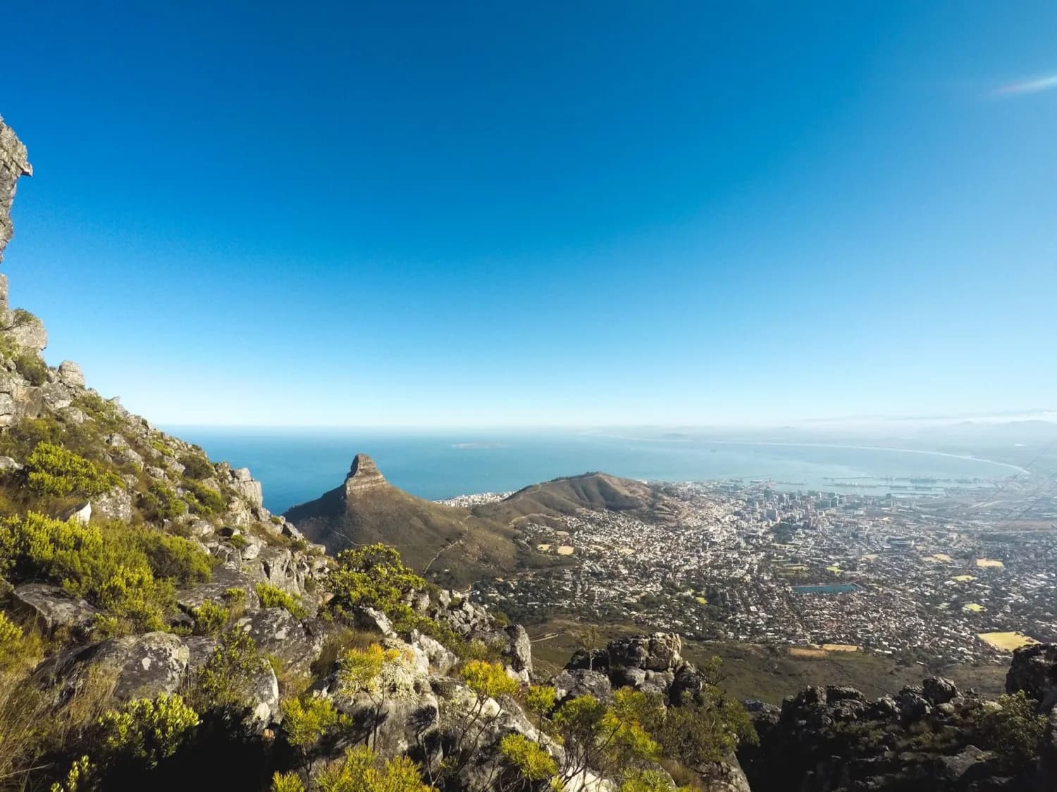 Blick von Tafelberg über Lion's Head, Kapstadt, mit Küste, Atlantik und Stadtpanorama bei klarem Himmel