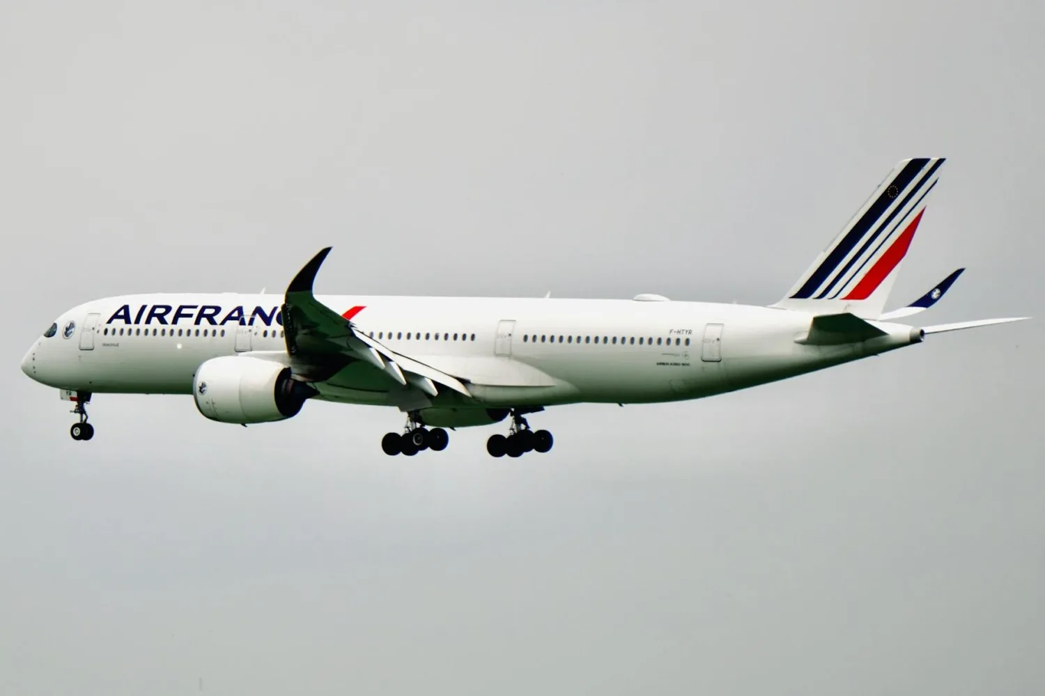 Air France Passagierflugzeug im Landeanflug mit ausgefahrenem Fahrwerk, langsamer Außenaufnahme der rechten Flugzeugseite, Markenlackierung und Heckflosse sichtbar