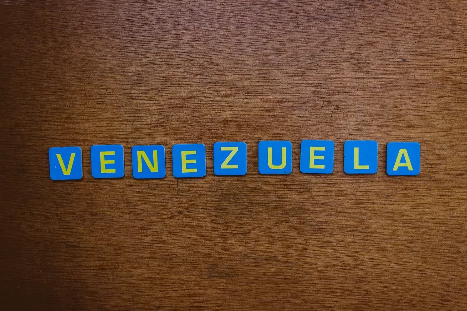 VENEZUELA Schriftzug aus blauen Holzbuchstaben auf braunem Holztisch