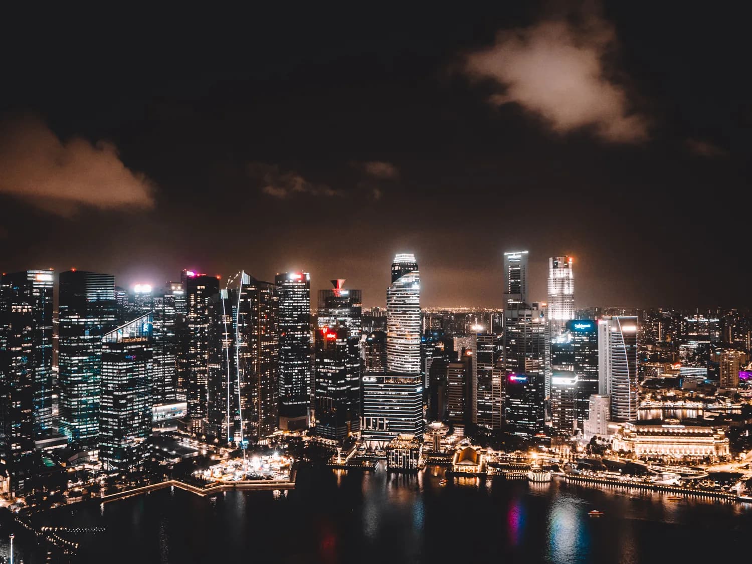 Nächtliche Skyline von Singapur mit beleuchteten Wolkenkratzern an der Marina Bay