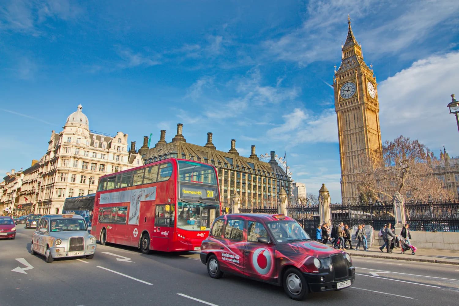Straßenszene in London mit rotem Doppeldeckerbus, schwarzem Taxi, Big Ben und Fußgängern vor historischen Gebäuden