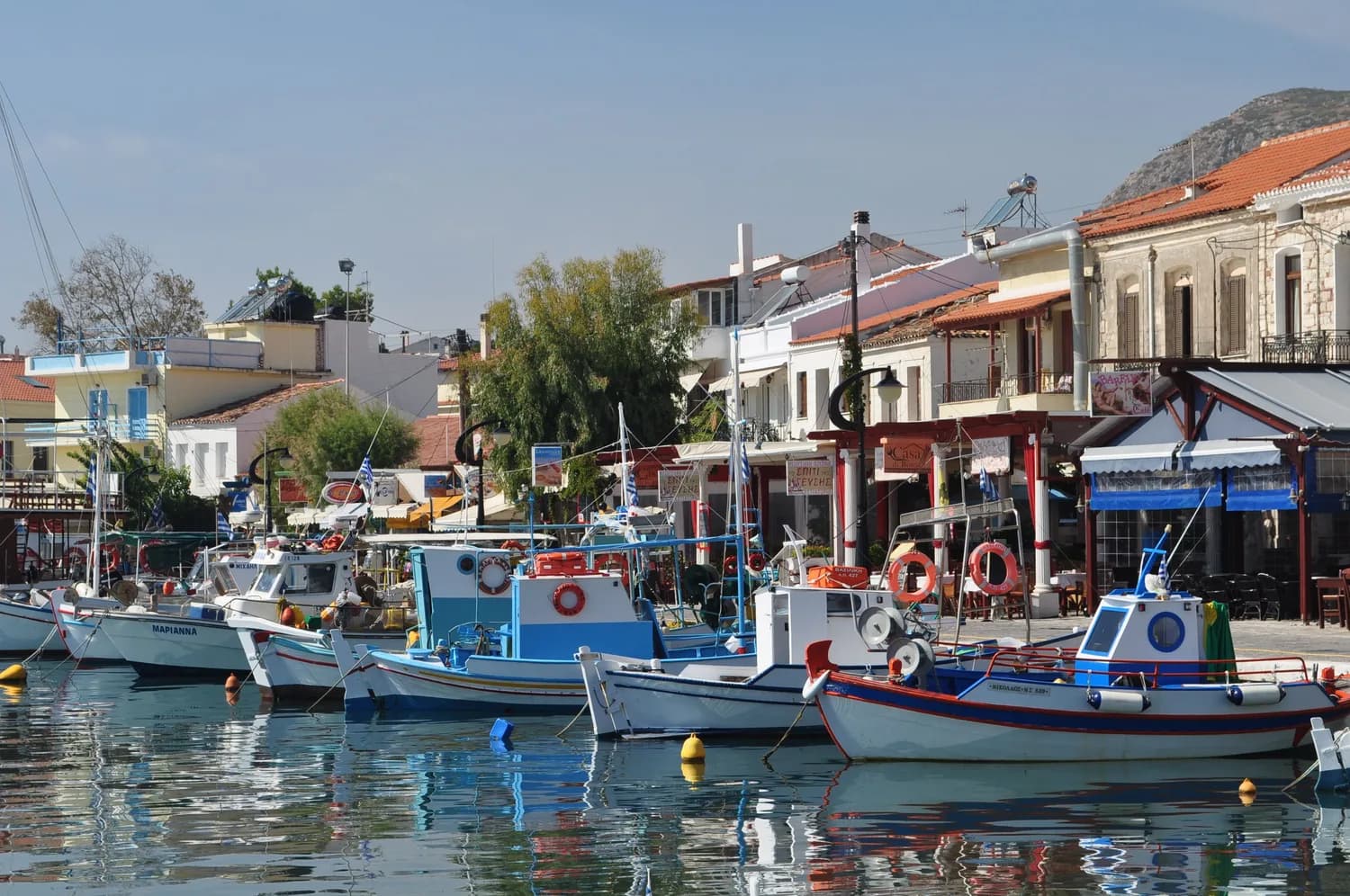 Kalamata Hafen mit bunten Fischerbooten im Wasser vor traditioneller griechischer Küstenarchitektur