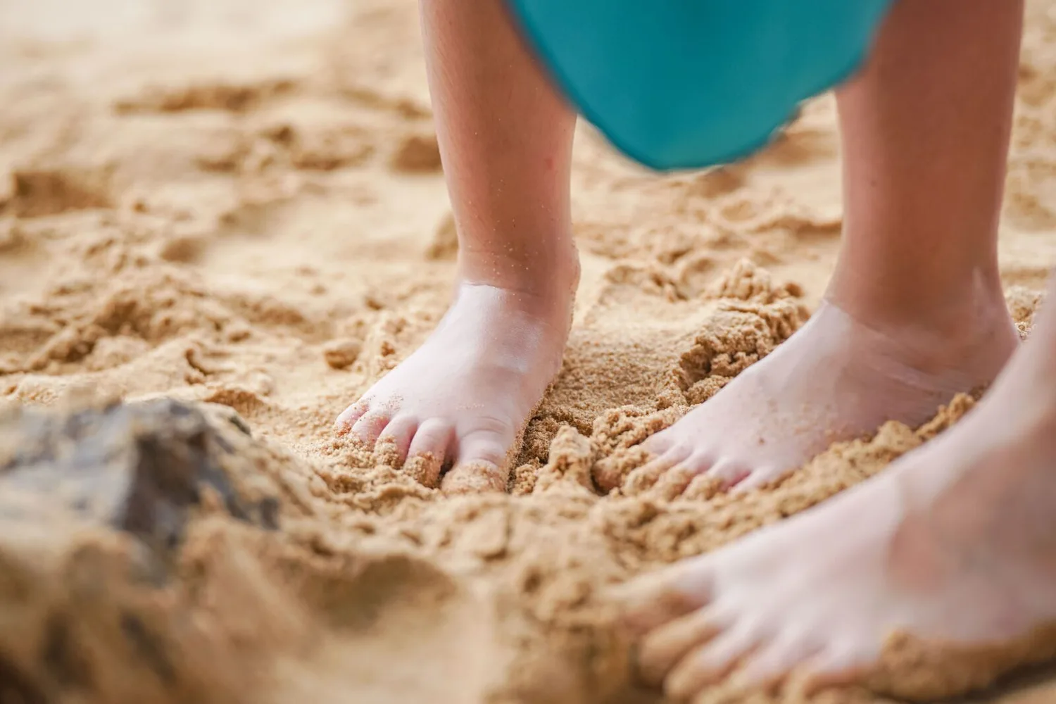 Kinderfüße im warmen Sand am Strand während der Sommerferien