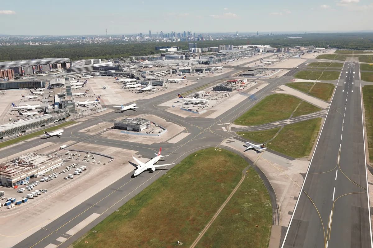 Luftaufnahme Flughafen mit Rollfeld, Start- und Landebahn, mehreren Passagierflugzeugen am Terminal und wartenden Taxiway-Fahrzeugen (c) Flughafen Frankfurt