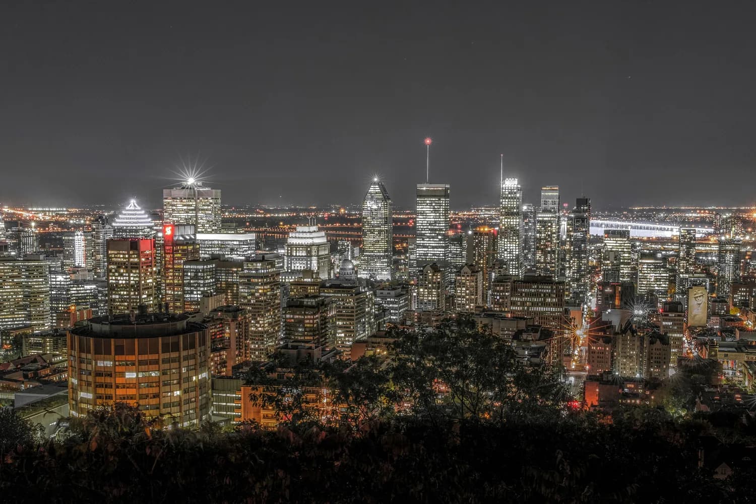 Montreal Skyline bei Nacht mit beleuchteten Wolkenkratzern, urbaner Innenstadt und Flussufer im Hintergrund