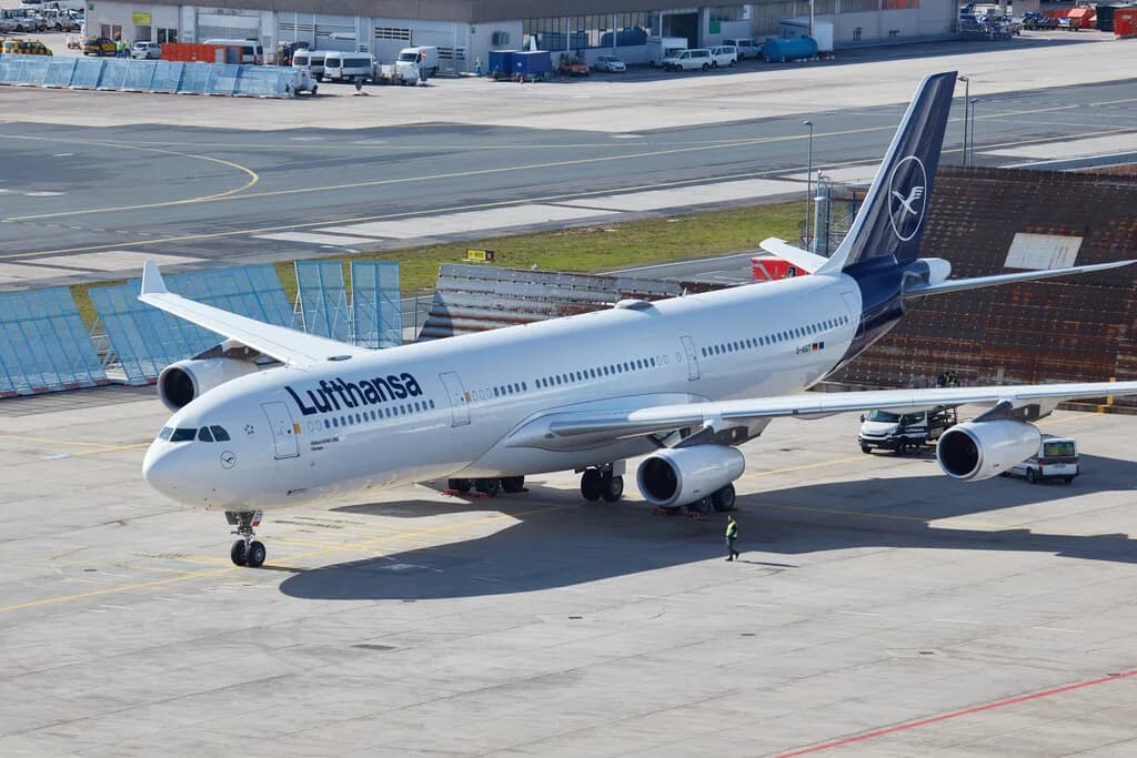 Lufthansa Großraumflugzeug A330 am Flughafenparkplatz mit Bodenpersonal und Servicefahrzeugen, Seitenansicht beim Taxiing