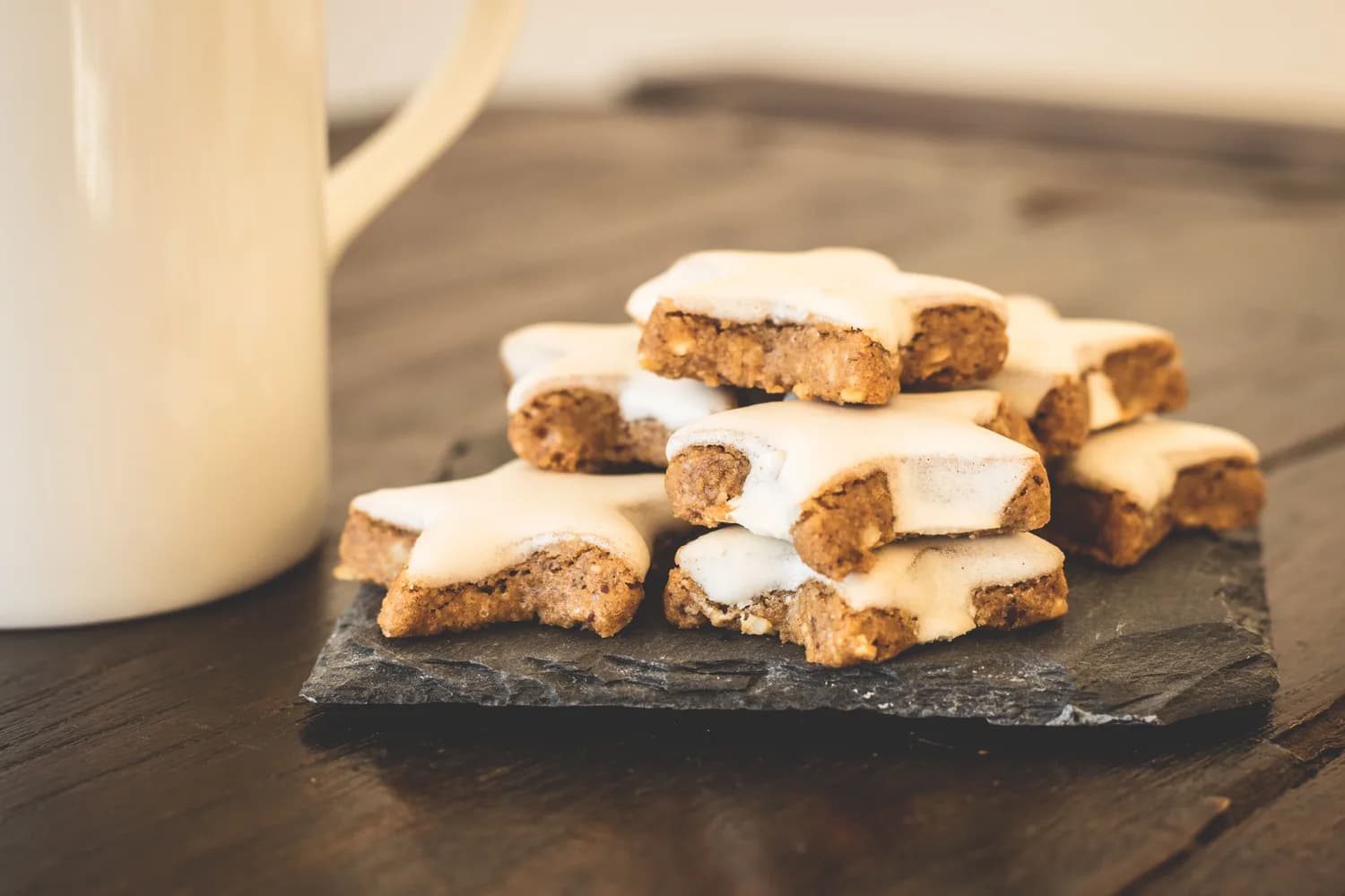 Zimtsterne mit Zuckerstreich auf Schieferplatte, Weihnachtsgebäck neben Tasse (Nürnberger Lebkuchen-Stil)