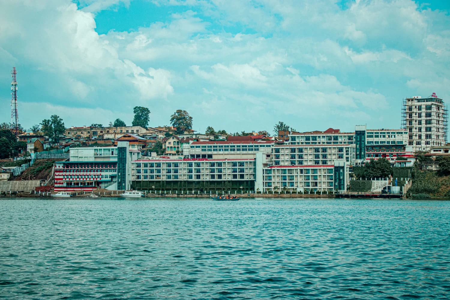 Uferpromenade von Bukavu am Kivusee mit mehrstöckigen Hotels und Gebäuden, Boot auf dem See, Stadtlandschaft in der Demokratischen Republik Kongo