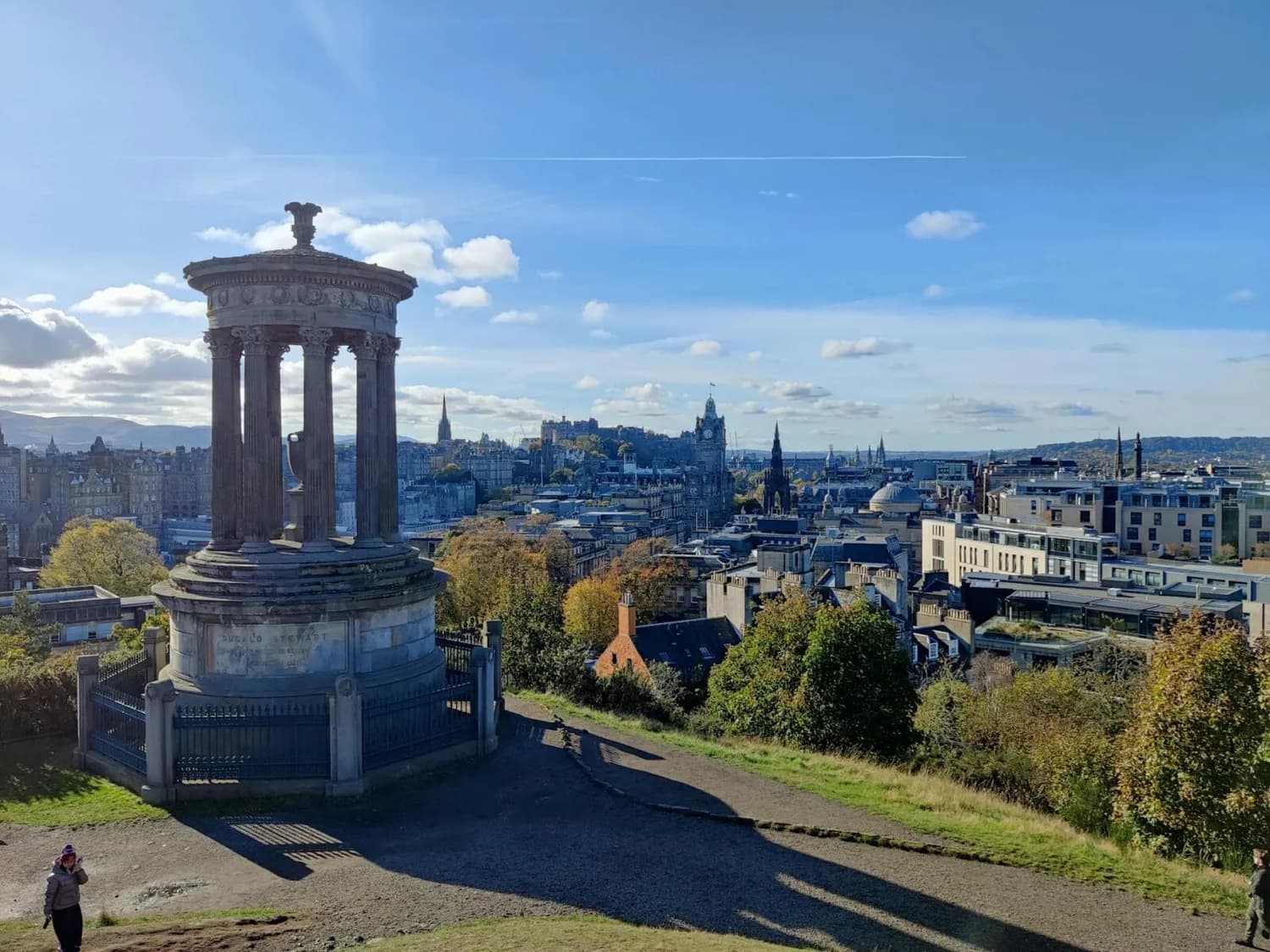 Dugald Stewart Monument auf Calton Hill mit Panorama der Altstadt von Edinburgh, Schloss und historischen Türmen bei klarem Himmel