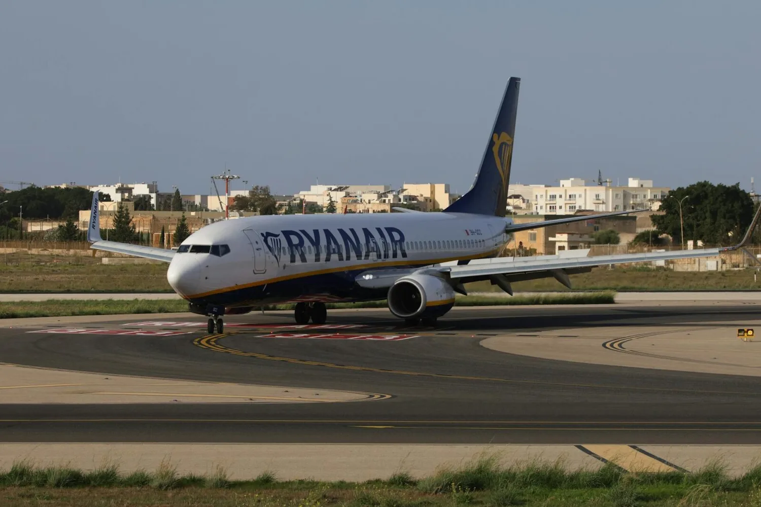 Ryanair-Passagierflugzeug Boeing 737 auf Rollweg am Flughafen vor Wohnbauten, Seitenansicht mit Markenlogo
