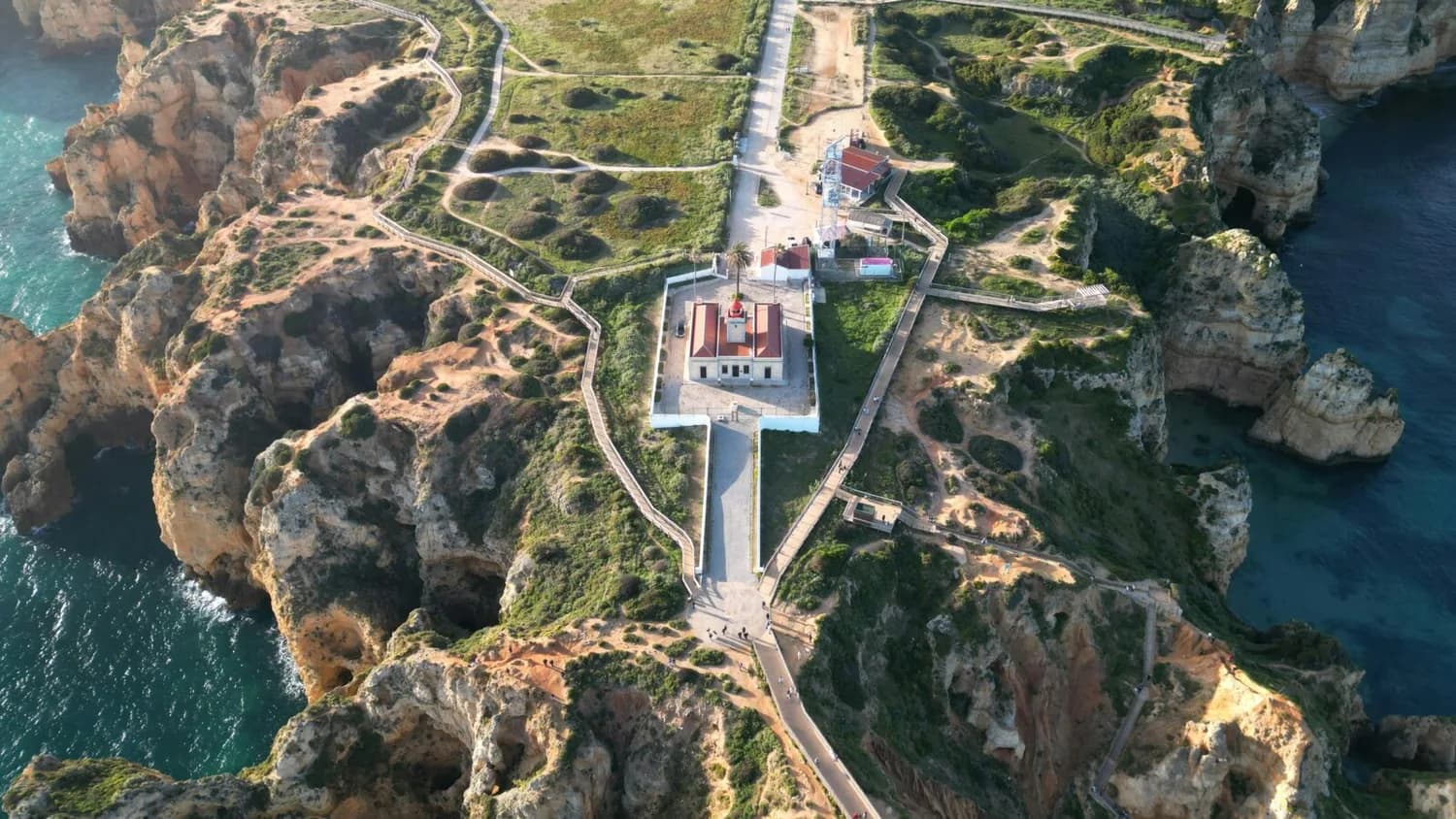 Luftaufnahme des Leuchtturms Ponta da Piedade und Küstenklippen bei Lagos, Algarve, Portugal, Spazierwege über gelbe Felsen und blaues Meer