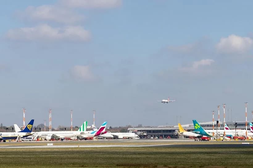 Flughafen Hamburg Vorfeld mit geparkten Linienmaschinen verschiedener Airlines und anfliegendem Flugzeug über Start- und Landebahn