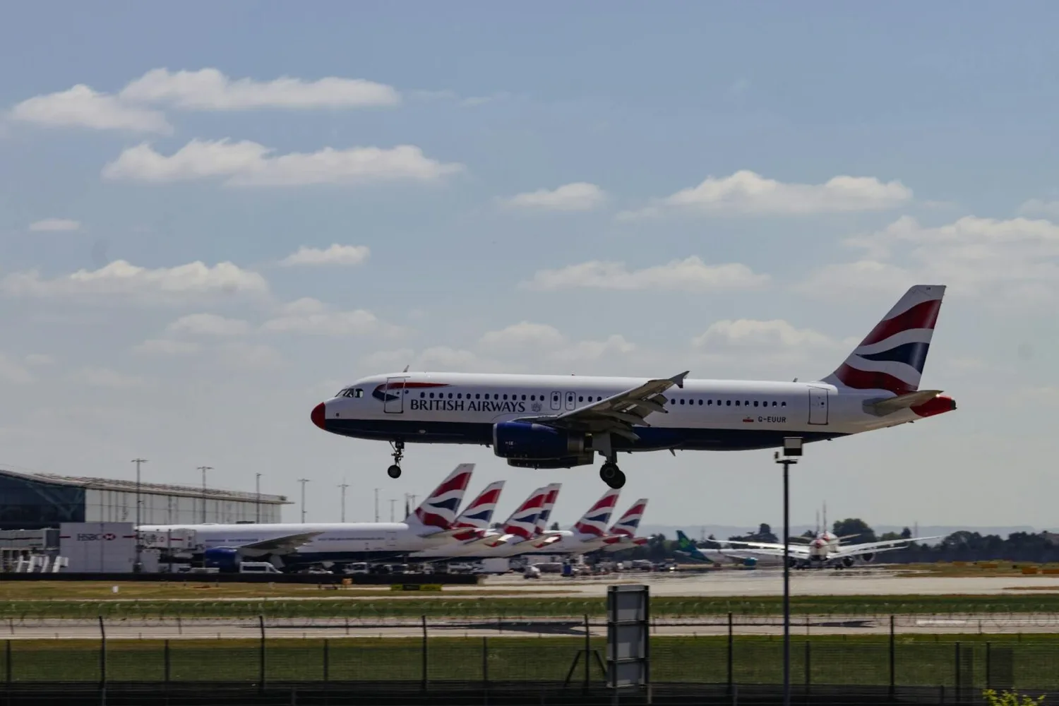 British Airways Passagierflugzeug landet über Startbahn am London Heathrow Flughafen mit geparkten BA-Tails im Hintergrund