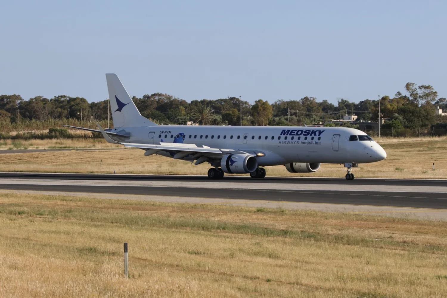 MedSky Airways Verkehrsflugzeug beim Rollen auf der Startbahn, weißes Passagierflugzeug mit Airline-Logo am Flughafen vor grasbewachsenem Vorfeld