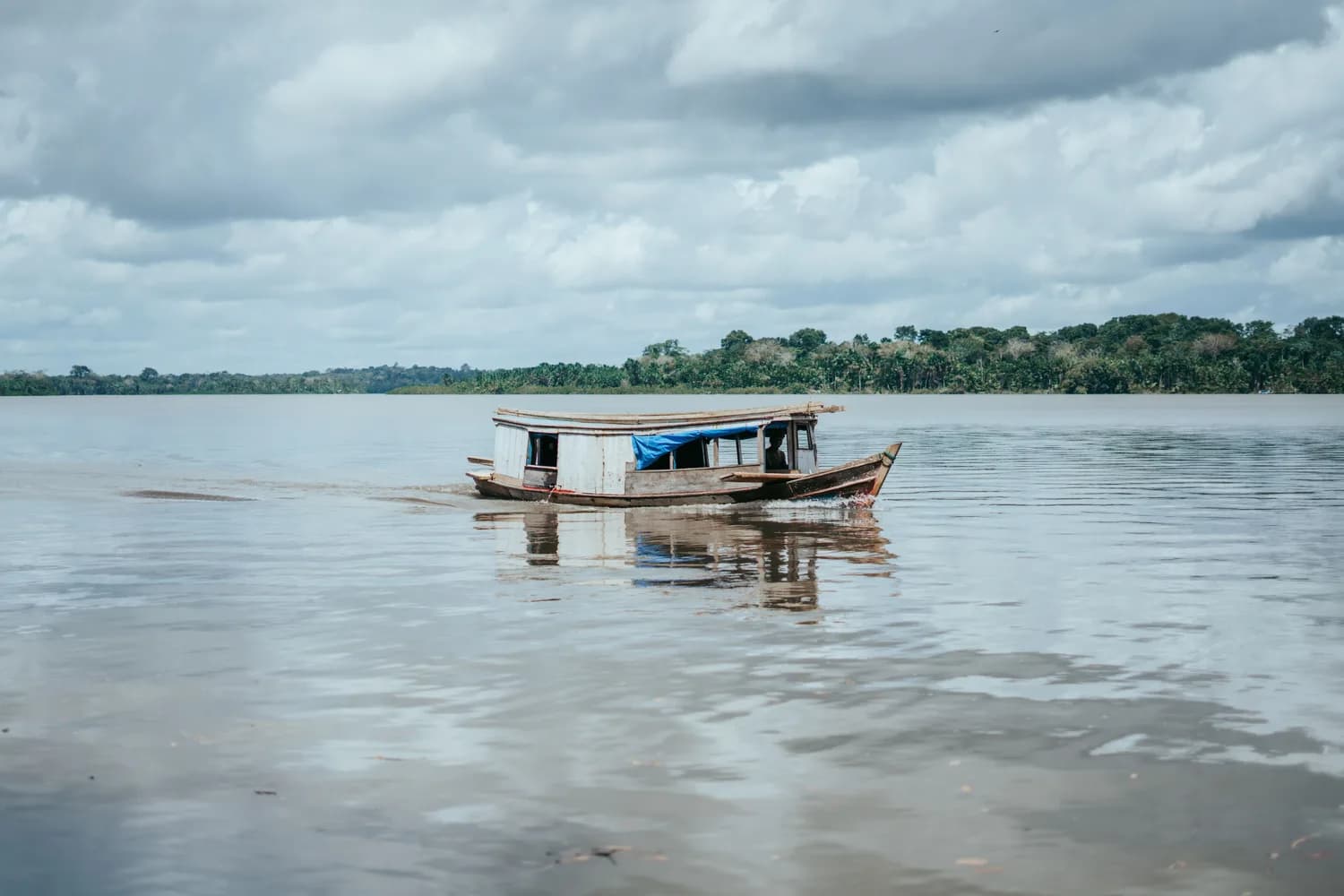 Holzboot auf einem Fluss im Amazonasgebiet, üppige tropische Vegetation am Ufer