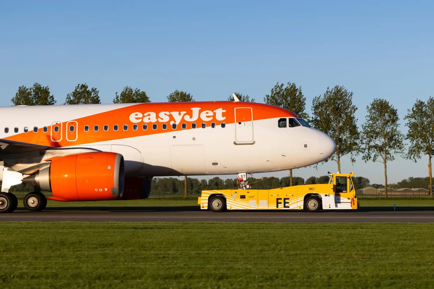 easyJet Passagierflugzeug wird von gelbem elektrischen Taxibot am Rollfeld geschleppt