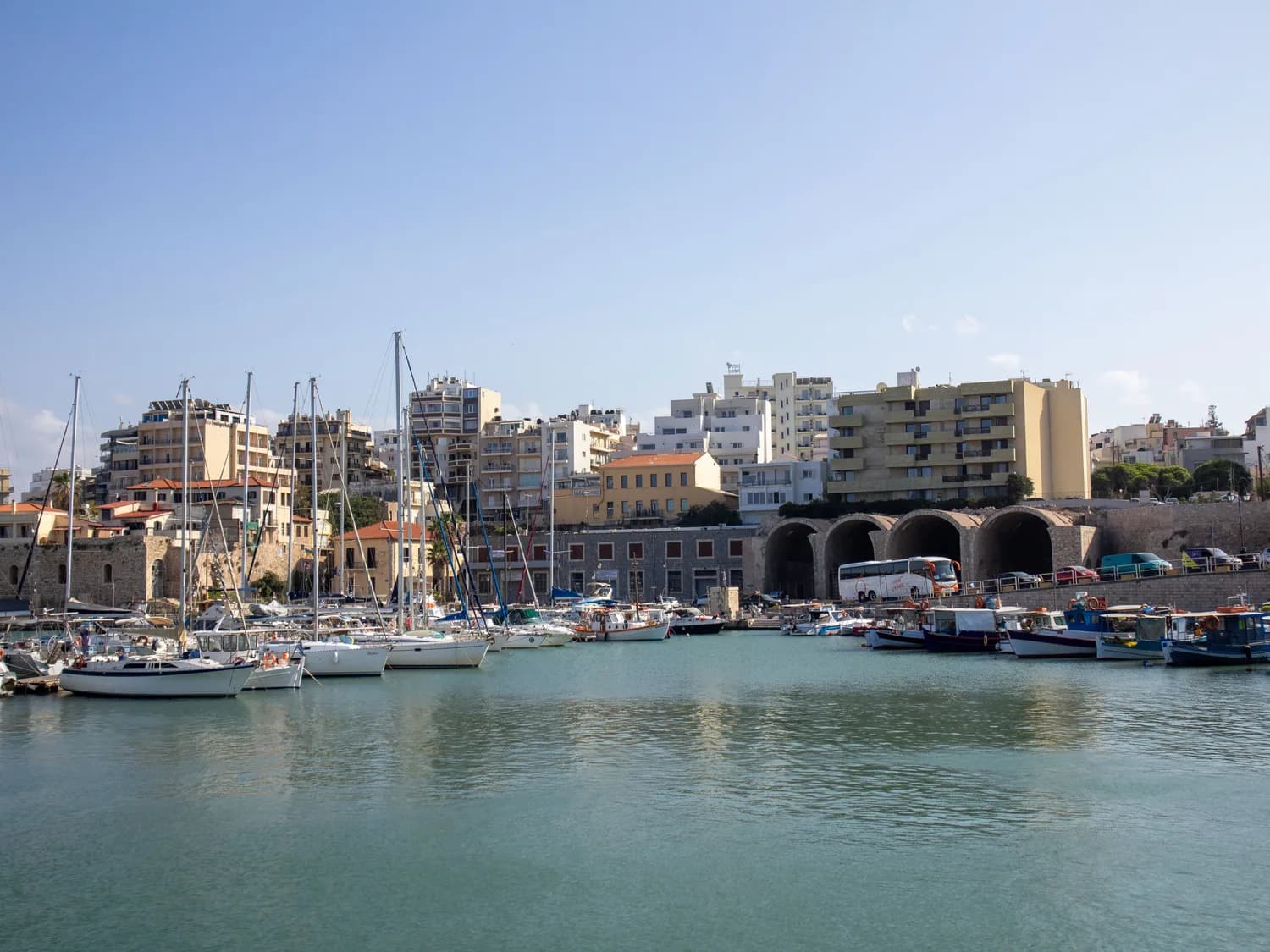 Jachten und Fischerboote im Hafen von Heraklion mit Hafenbauten und Stadtansicht von Kreta