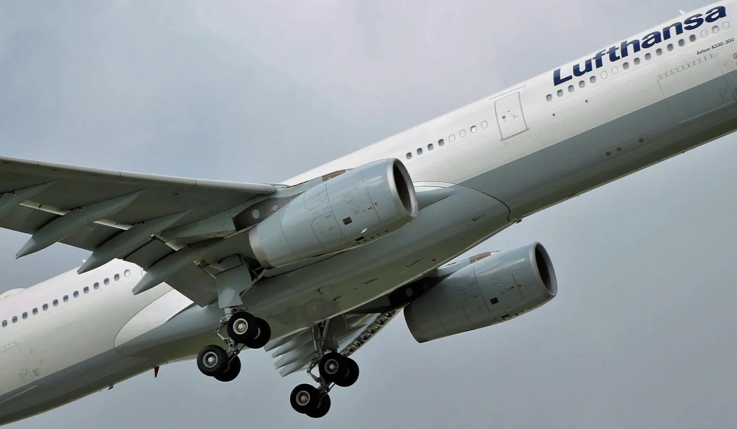 Lufthansa Passagierflugzeug im Steigflug mit ausgefahrenem Fahrwerk und Triebwerken sichtbar