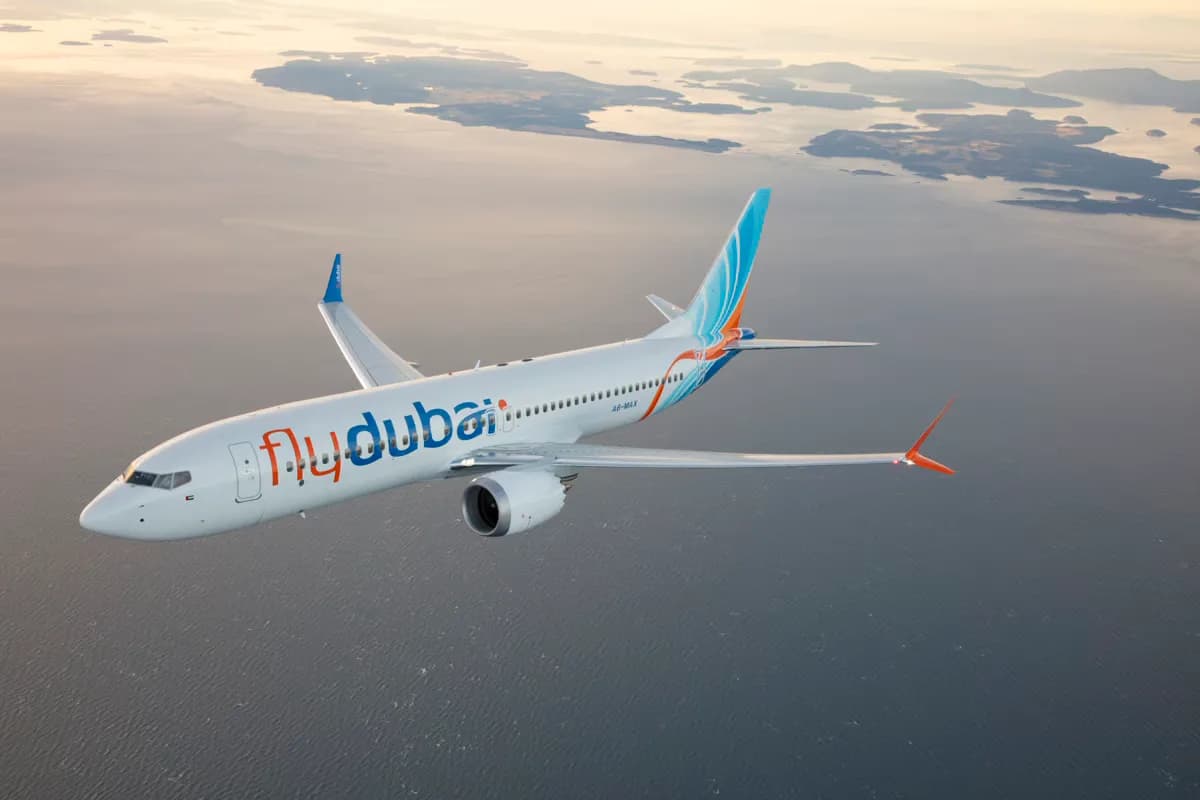 flydubai Passagierflugzeug Boeing über ruhiger Küstenlandschaft bei Dämmerung, Seitenansicht mit Airline-Branding