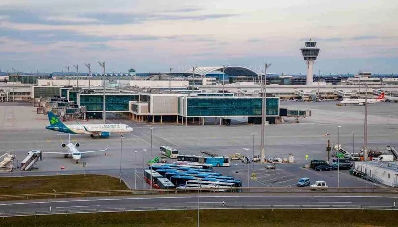 Flughafen München Pier mit Gate-Bereich, Passagierbusse, geparkten Flugzeugen und Kontrollturm im Hintergrund