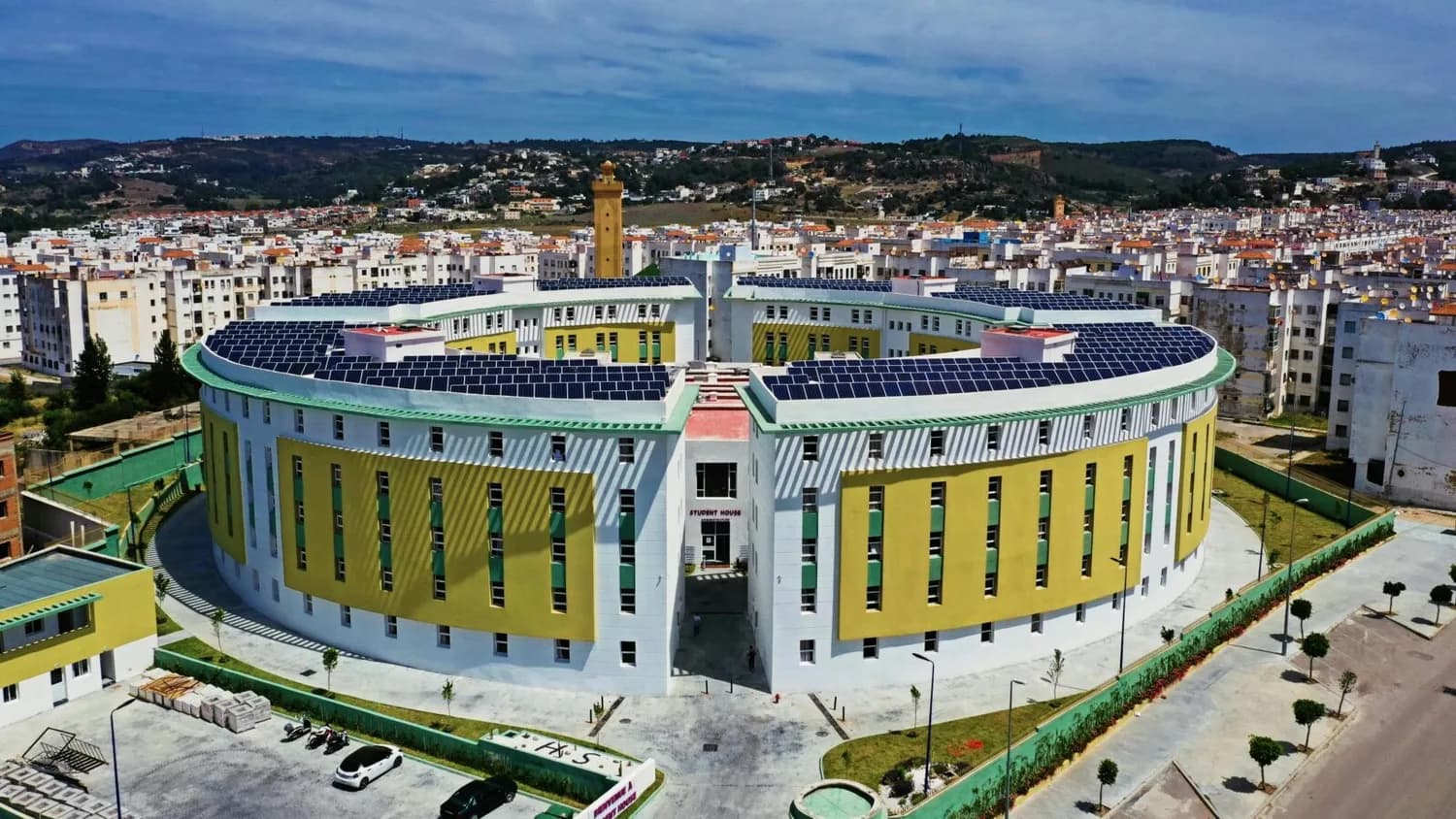 Luftaufnahme eines runden Studentenwohnheims mit Solarpaneelen auf dem Dach vor der Stadtlandschaft von Tanger, Marokko