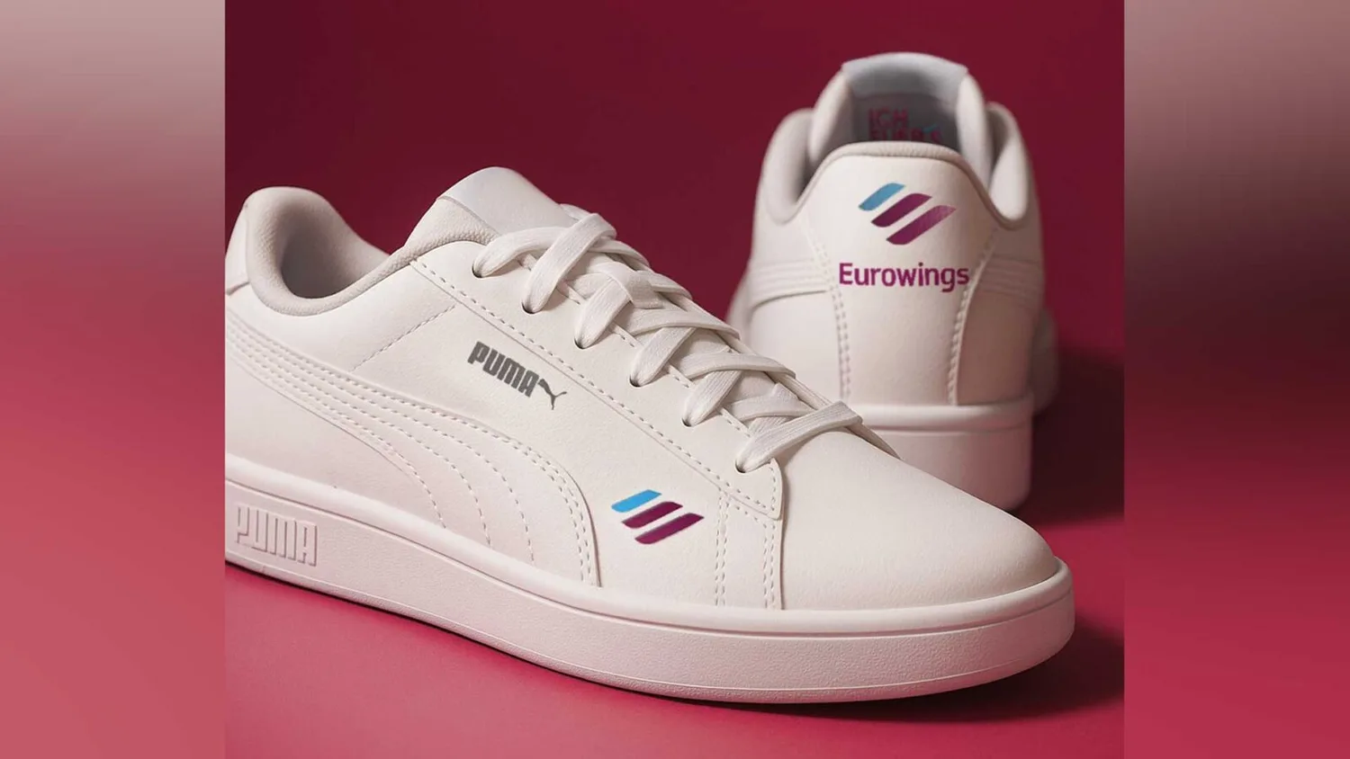Weiße Puma Sneaker mit Eurowings-Branding auf rosa Hintergrund, Seiten- und Fersenansicht des Logos und dezenter sportlicher Designstil