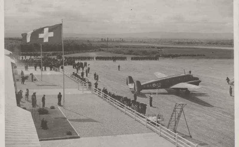Inaugurationsszene auf Flugfeld mit Passagierflugzeug F-BAO, Schweizer Flagge, Empfangsbereich und Zuschauern beim Festakt