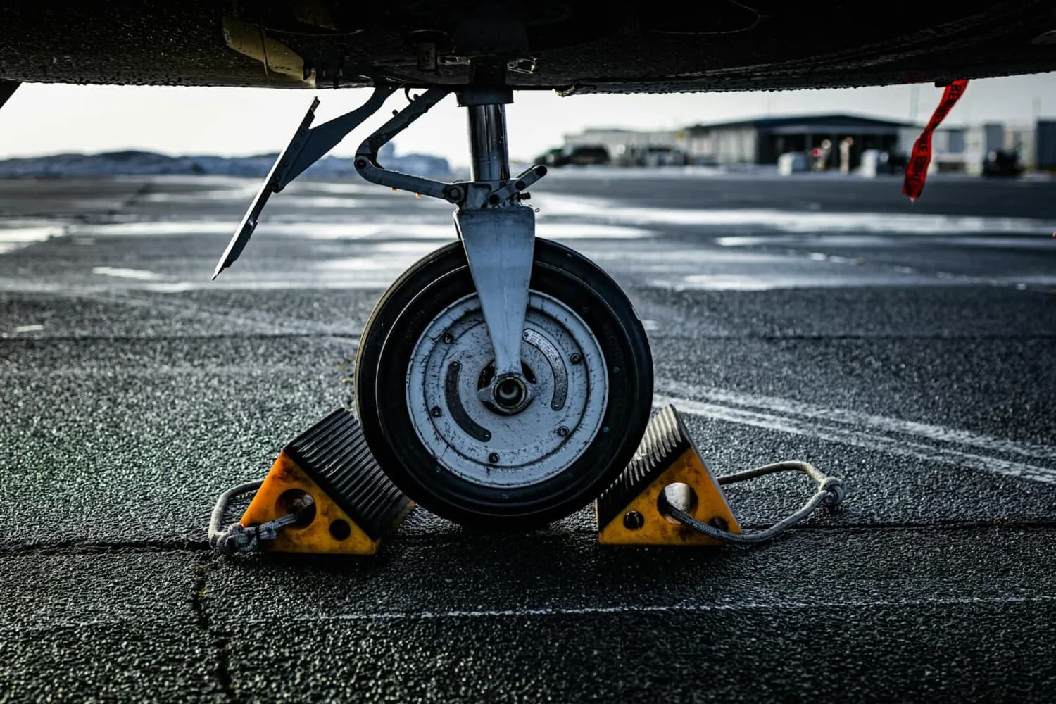Flugzeugnasefahrwerk mit Reifen auf Rampenboden gesichert durch gelbe Keile, Nahaufnahme des Onblock/Offblock-Radsystems