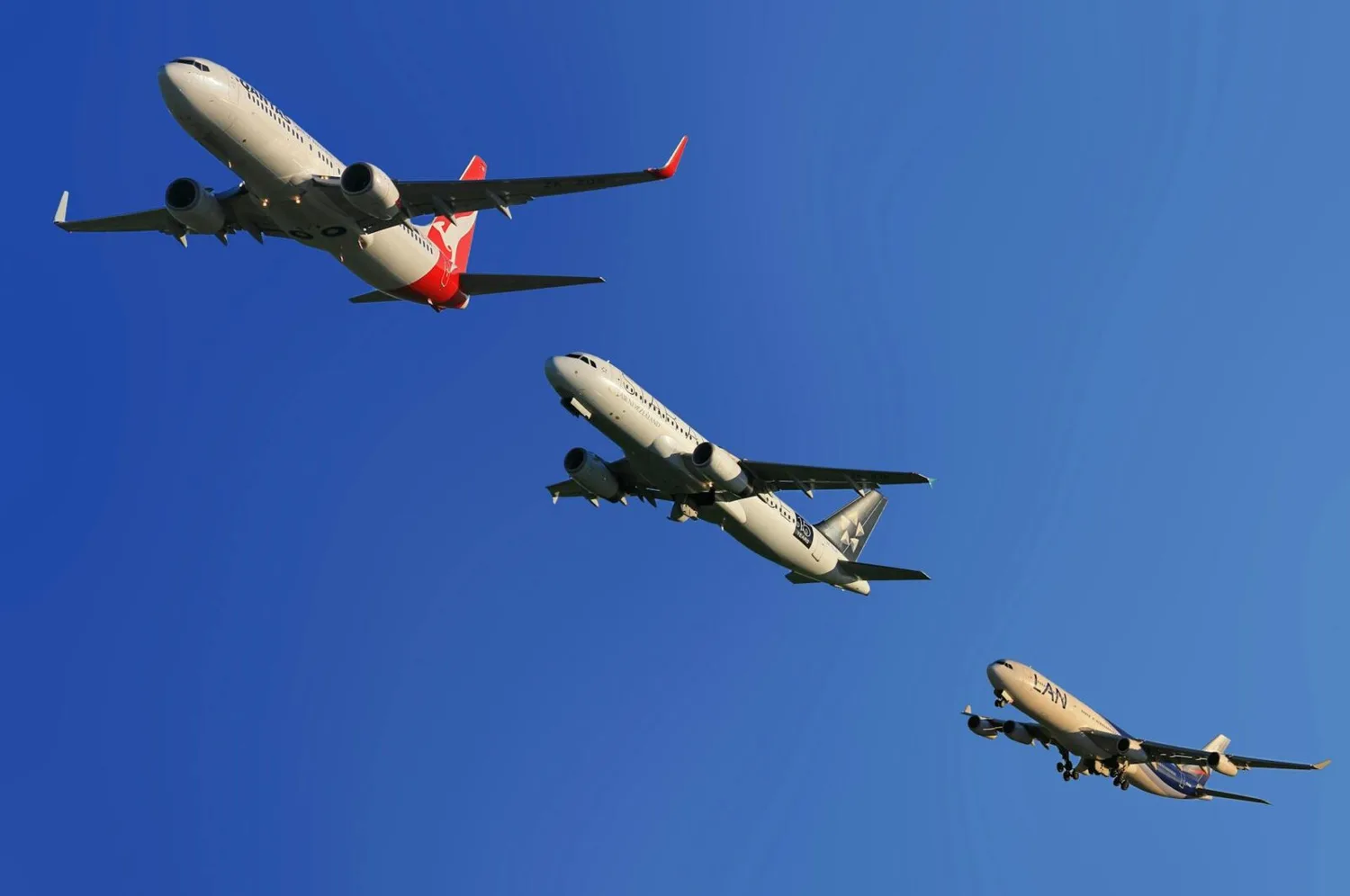 Drei Verkehrsflugzeuge in Formation über klarem blauem Himmel, Passagierjets beim Anflug und Symbol für Luftverkehrssicherheit