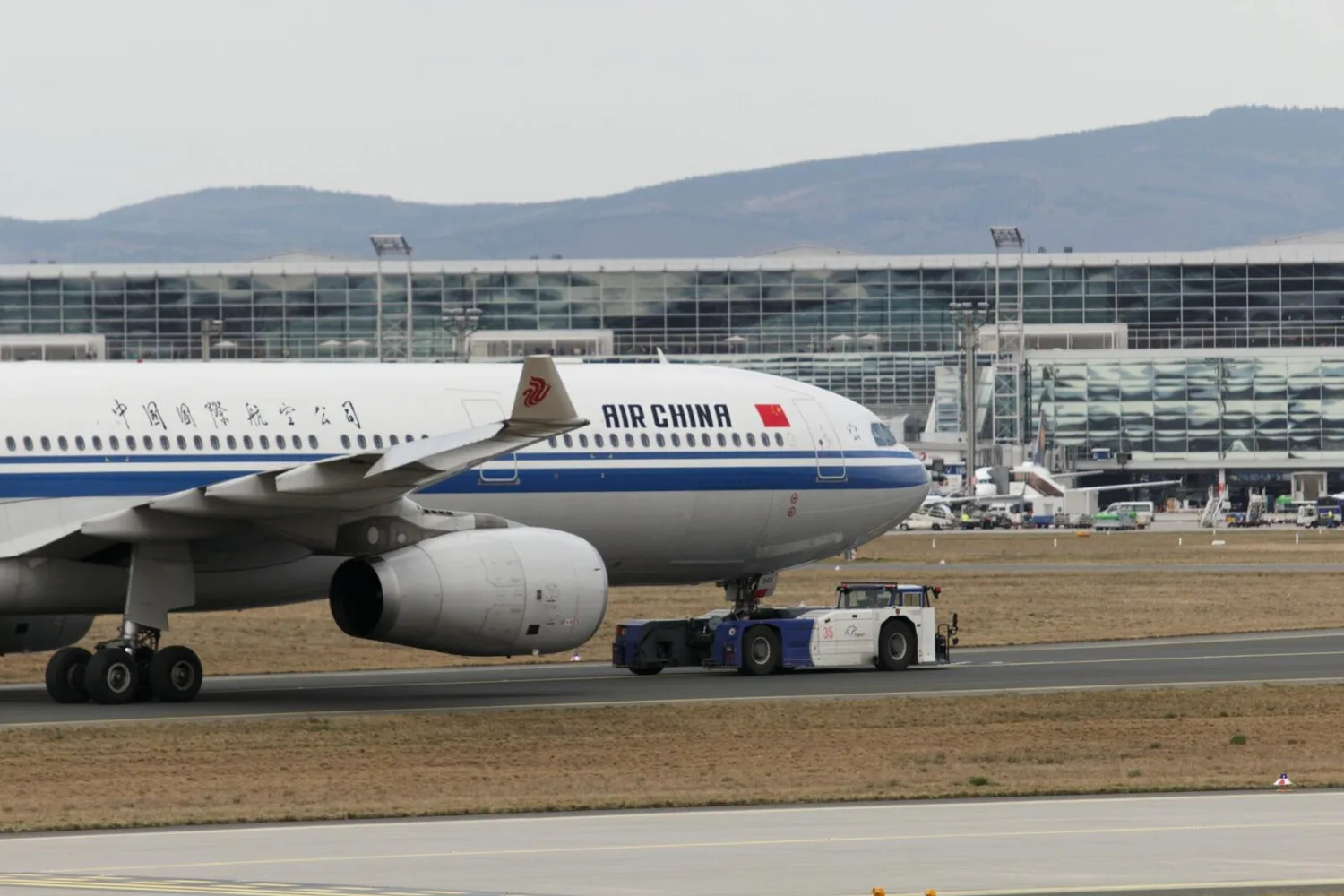Air China Passagierflugzeug wird am Flughafen Frankfurt von Schlepper über Startbahn zum Terminal gezogen