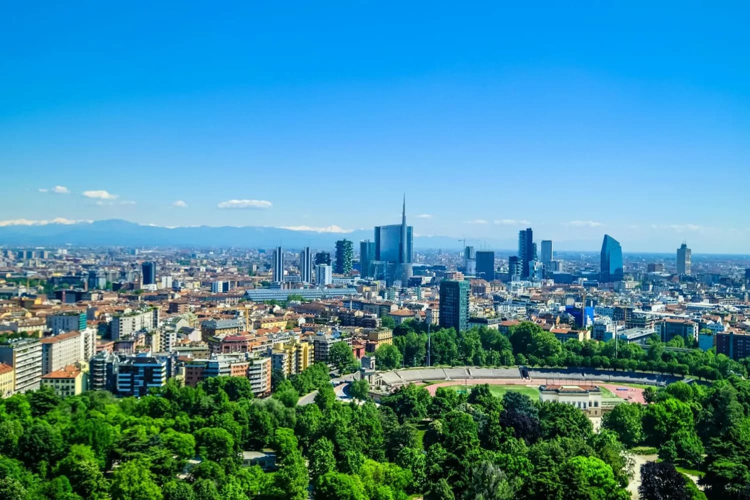 Panoramablick auf Mailand Skyline mit modernen Wolkenkratzern, Wohngebieten und grünen Parkanlagen, Stadtsilhouette bei klarem Himmel (Flugverbindung Mailand–Dortmund)