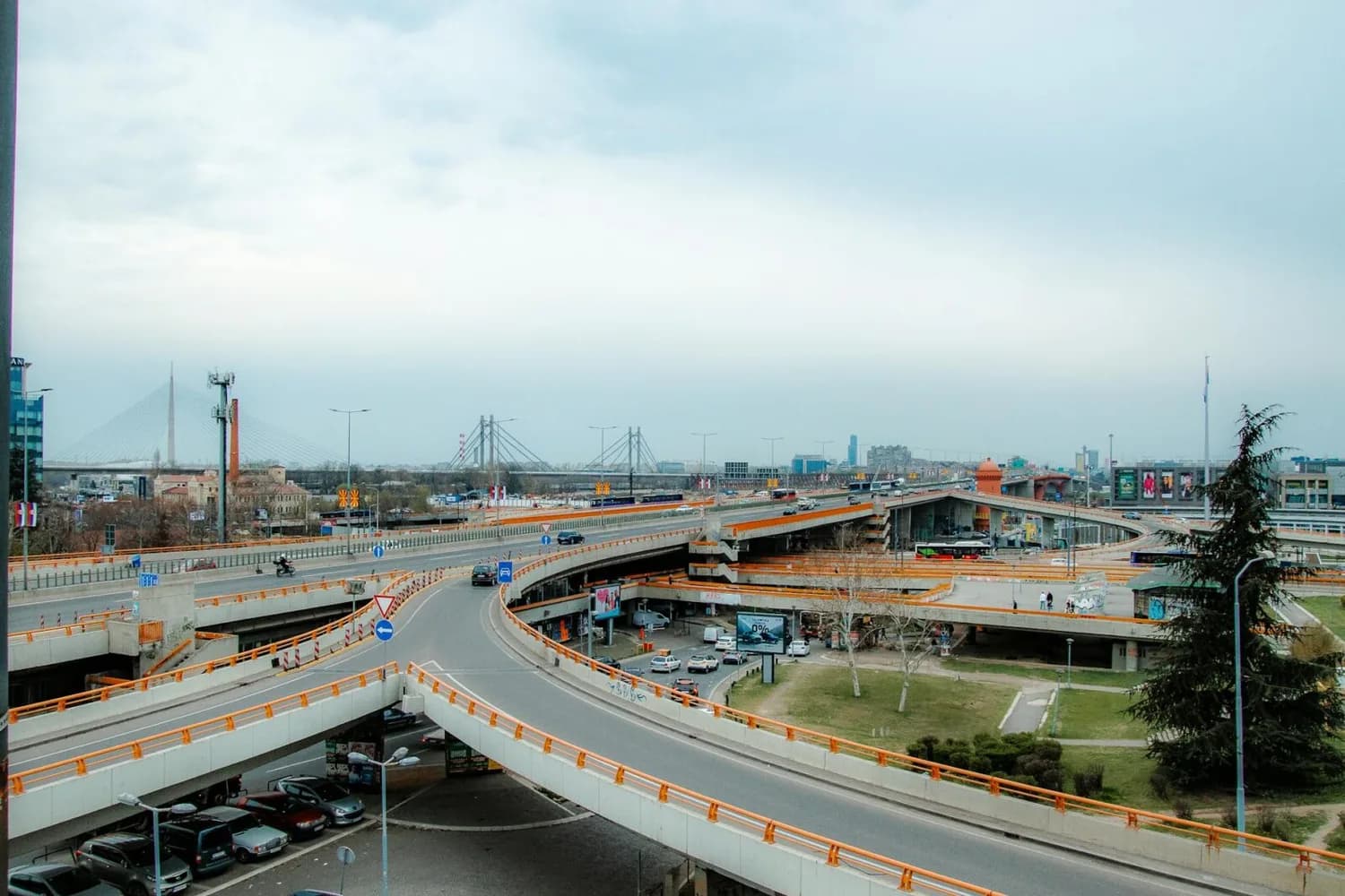 Autobahnkreuz und Hochstraßen mit Geländer in Orange, Brückenpylone und Donauufer im Hintergrund, städtische Verkehrsszene in Belgrad Serbien