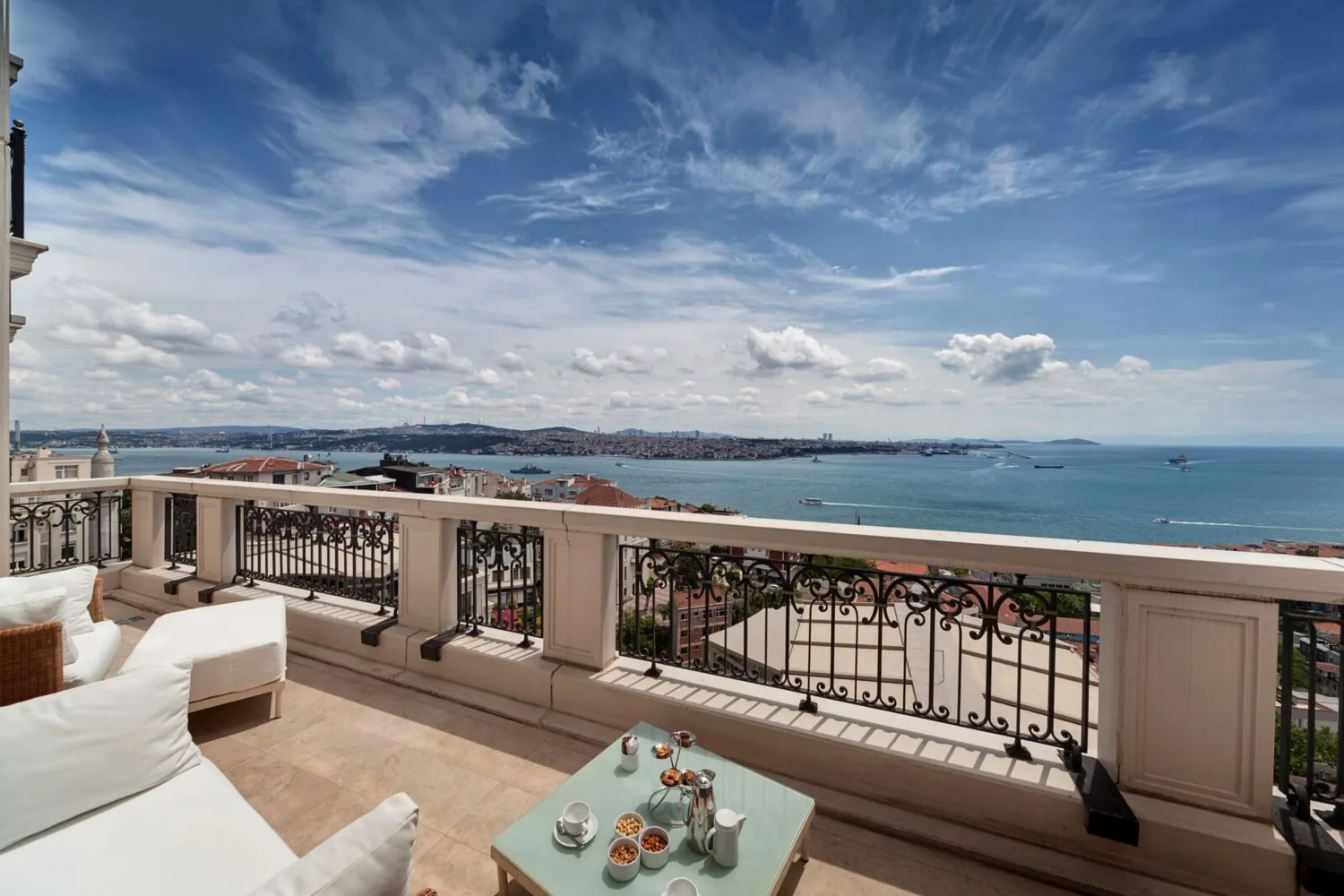 Balkonterrasse des CVK Park Bosphorus Hotels mit Lounge-Möbeln, Tisch mit Kaffee und Snacks und weitem Blick auf den Bosporus und die Küstenlinie Istanbuls