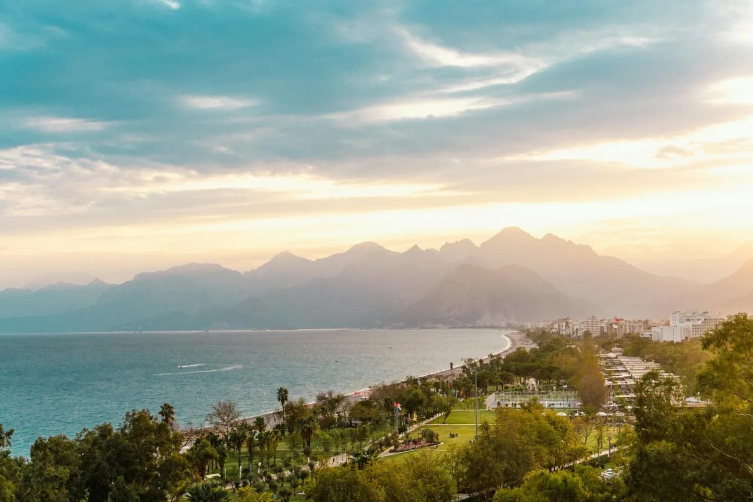 Antalya Küste mit Strandpromenade, Parkanlagen, Palmen und Bergpanorama bei Sonnenuntergang – Urlaubsziel für Flugreise nach Antalya