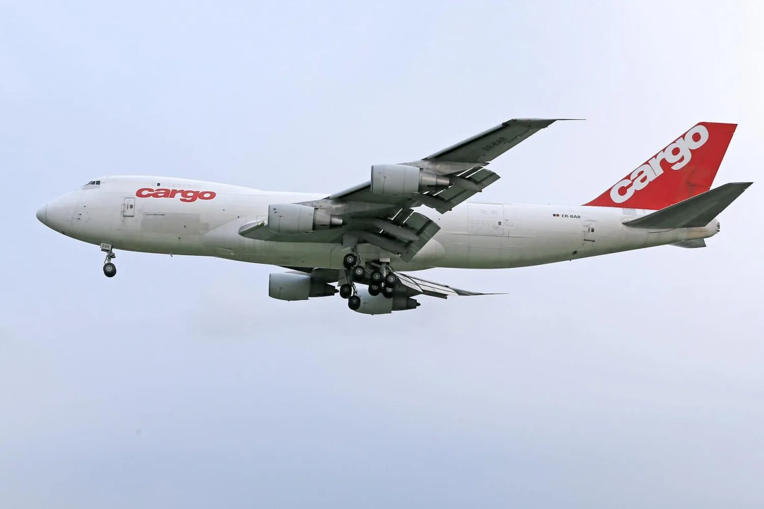 Frachtflugzeug Boeing 747 Belly Cargo mit ausgefahrenem Fahrwerk und roten „cargo“-Logo beim Landeanflug