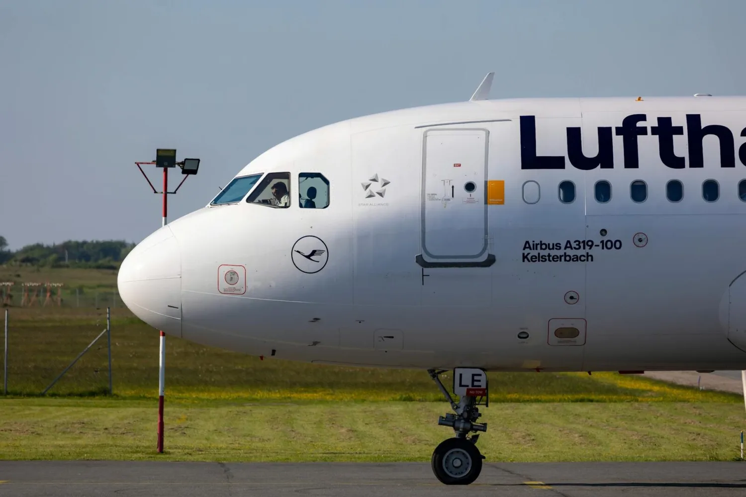 Lufthansa Airbus A319-Kabine und Cockpit beim Taxiing am Flughafen – Pilot am Fenster, Airline-Logo und Bugrad sichtbar, Hinweis auf Streik Lufthansa April